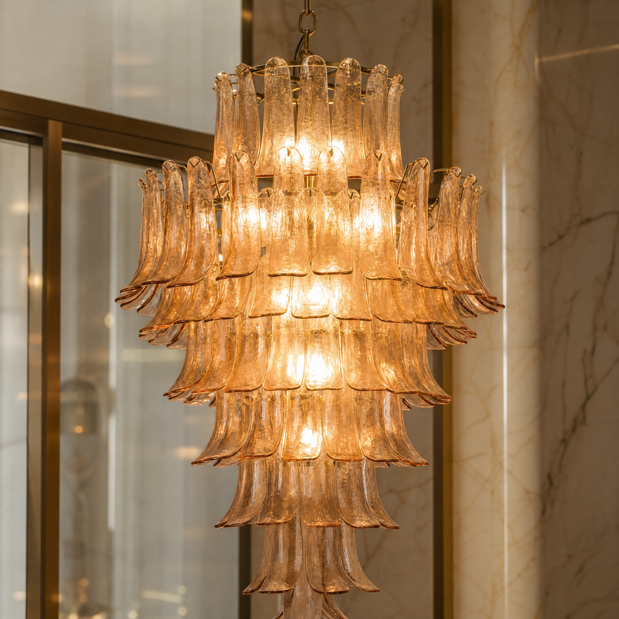 Detailed macro shot of the VORELLI Piccaro Grandeur chandelier, highlighting the individually hung curved amber glass petals mounted on a premium satin brass frame.