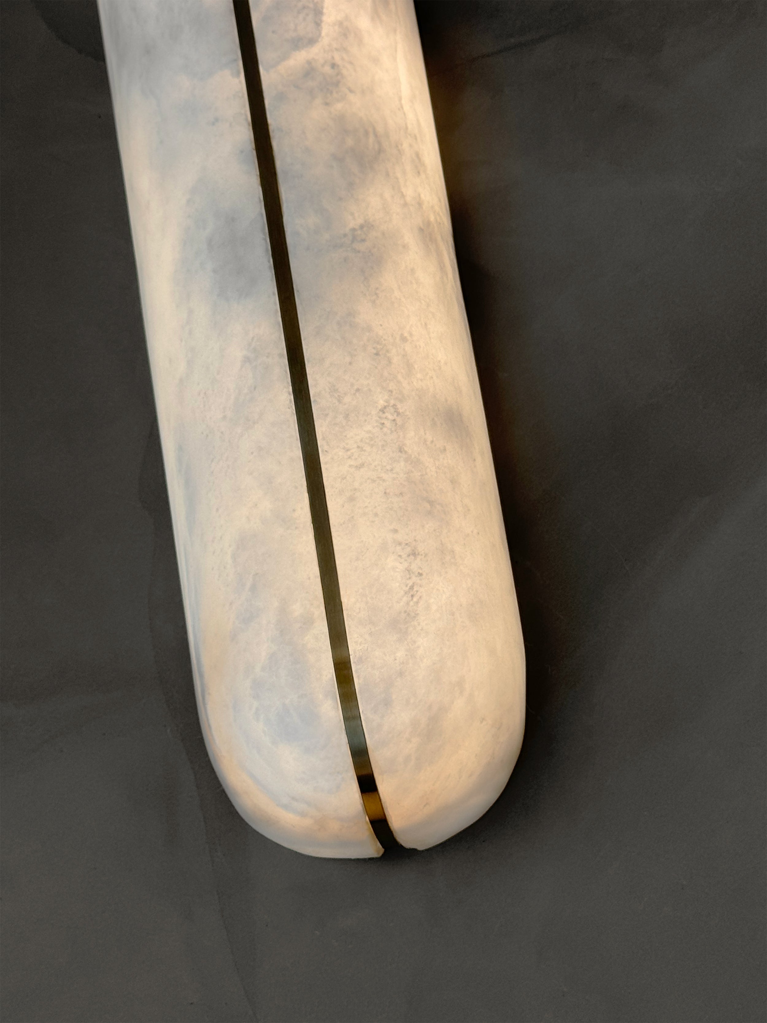 Close up of smooth elongated marble surface and subtle accent detailing on Serino wall light