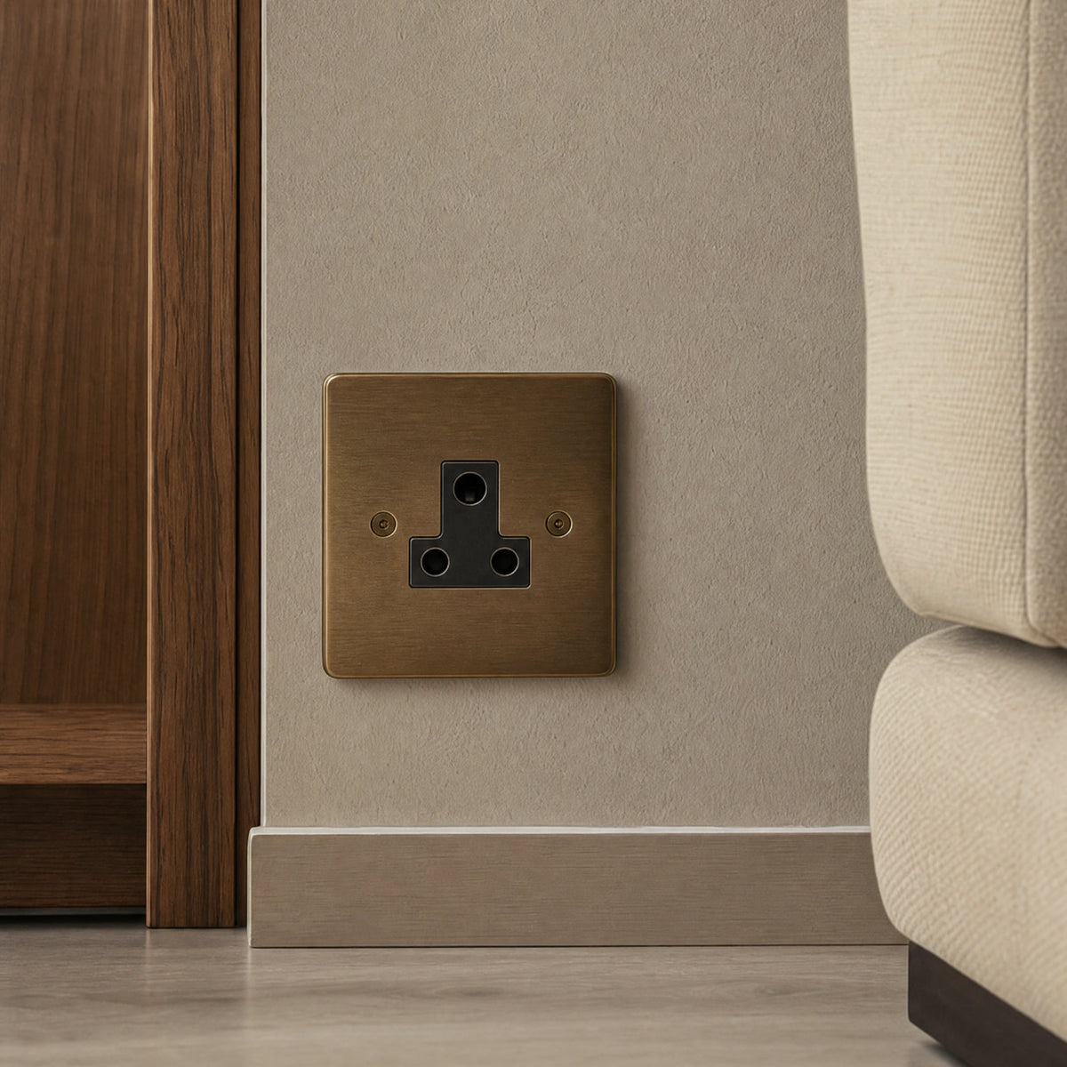 Close-up of a luxury antique brass 5a socket installed within bespoke bedside joinery or low-level wall beside a luxury seating area by VORELLI®.