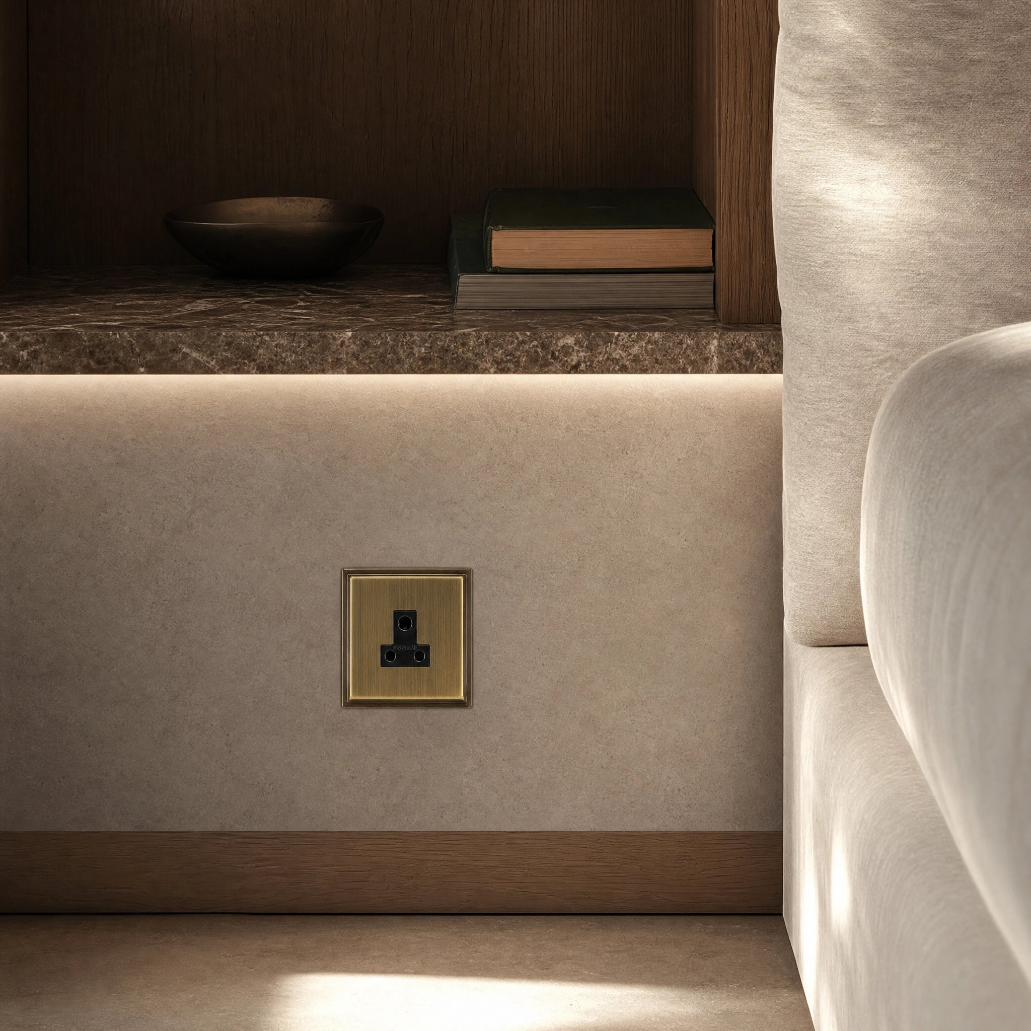 Luxury antique brass 5a socket installed within bespoke bedside joinery or low-level wall beside a luxury seating area in a UHNW interior by VORELLI®.