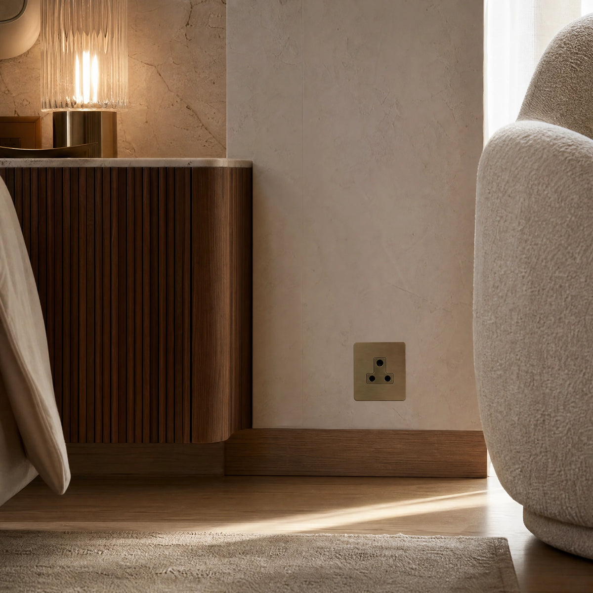 Luxury antique brass 5a socket installed within bespoke bedside joinery or low-level wall beside a luxury seating area in a UHNW interior by VORELLI®.