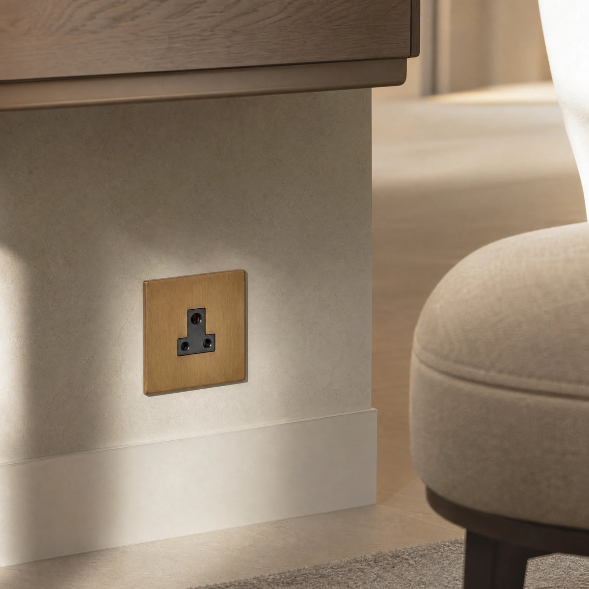 Close-up of a luxury sienna 5a socket installed within bespoke bedside joinery or low-level wall beside a luxury seating area by VORELLI®.