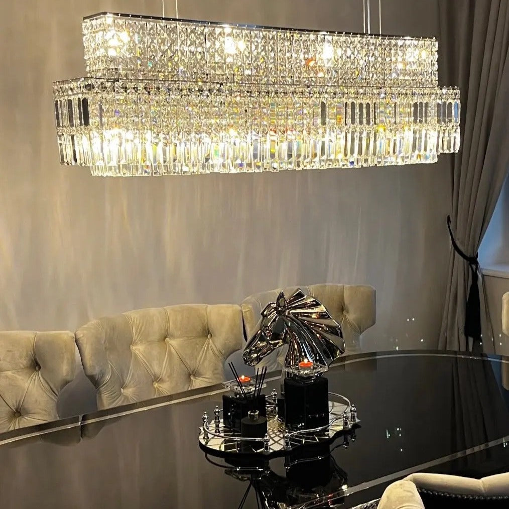 Ambient evening shot of the Abruzzi Rectangular Chandelier illuminating a luxury kitchen island.