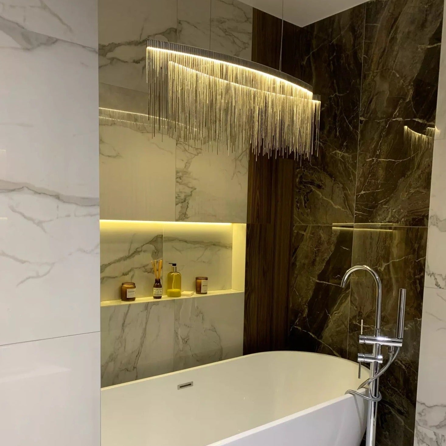 The Adlington Arc Rectangular Chandelier illuminated in a modern dining room setting, casting a warm ambient glow.