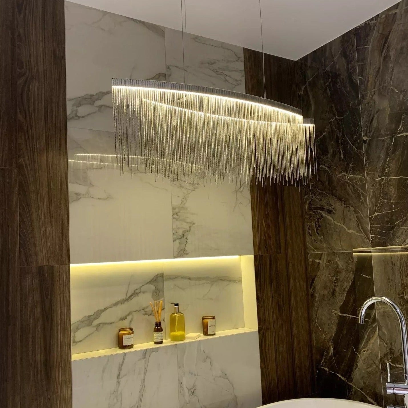 Side view of VORELLI® Adlington Arc Chandelier above a marble-topped table with chain fringe