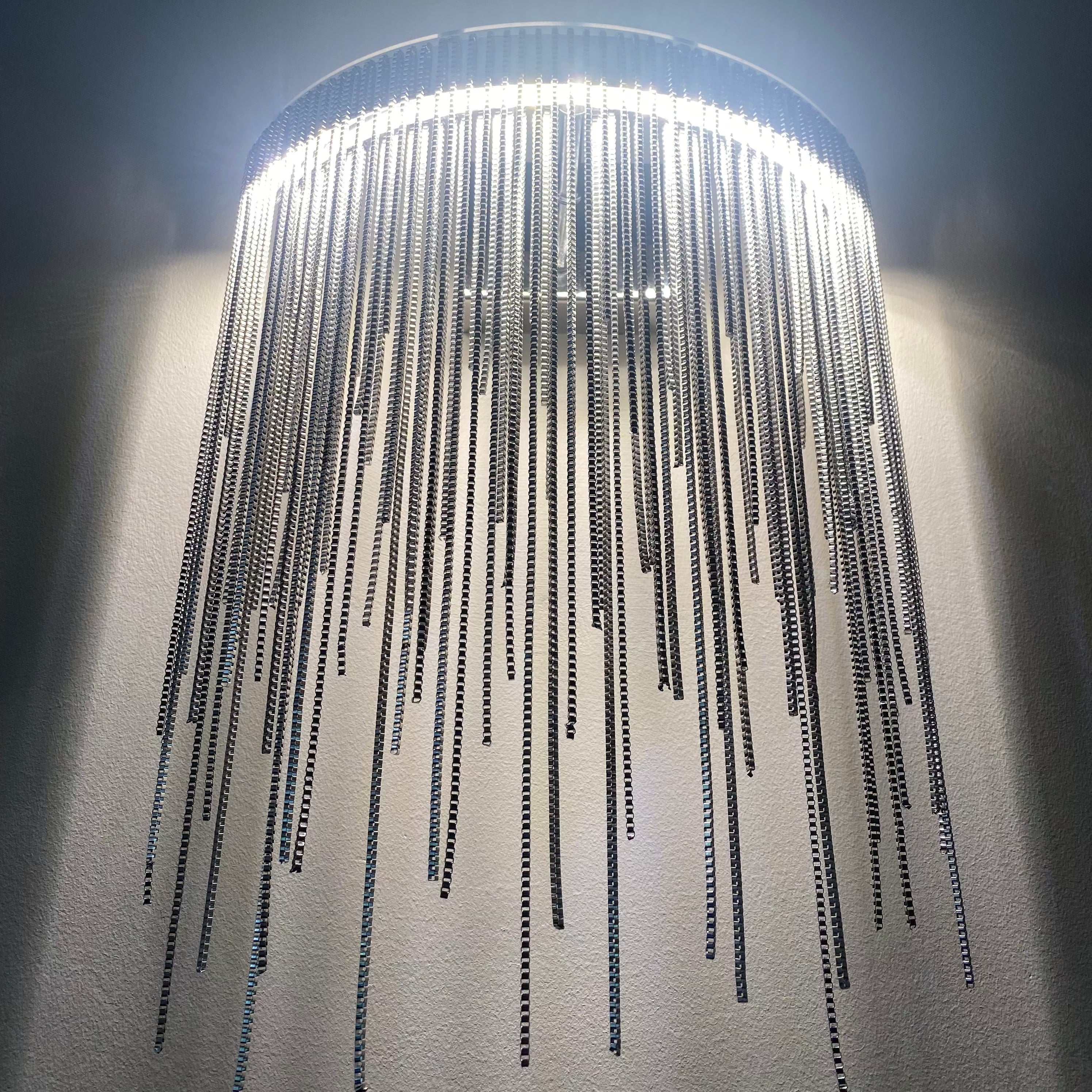 Angled perspective of the Adlington Wall Light by VORELLI, revealing the delicate layering of individual metal chains.