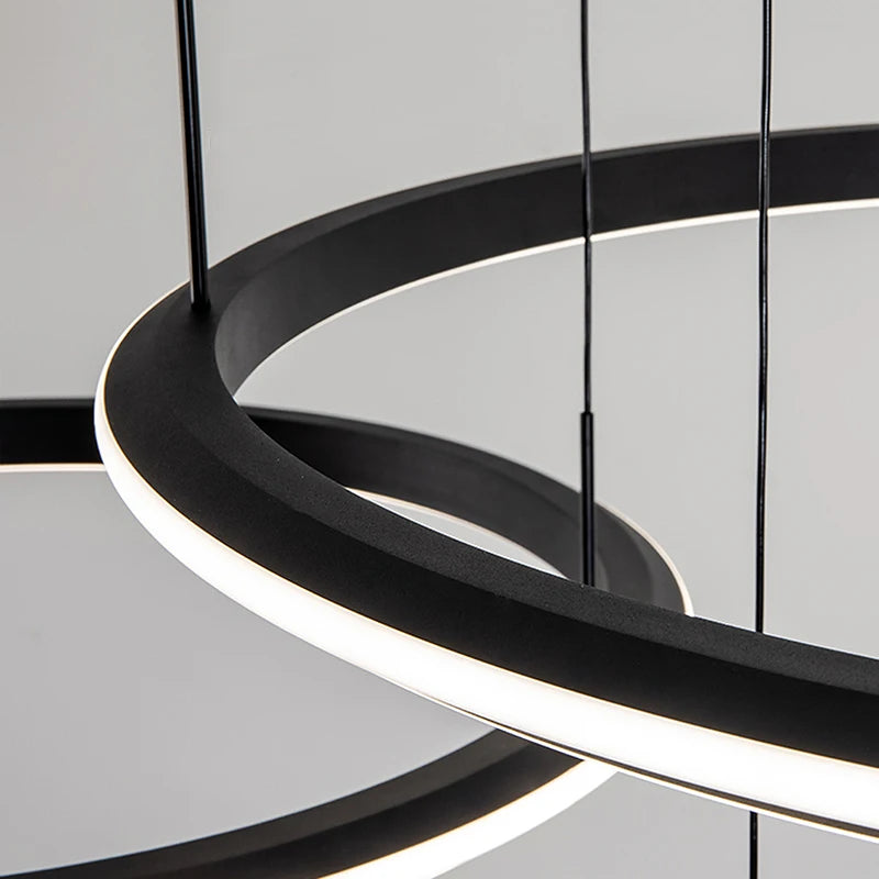 Close-up detail of the Bellezza trio chandelier’s curved LED ring design.