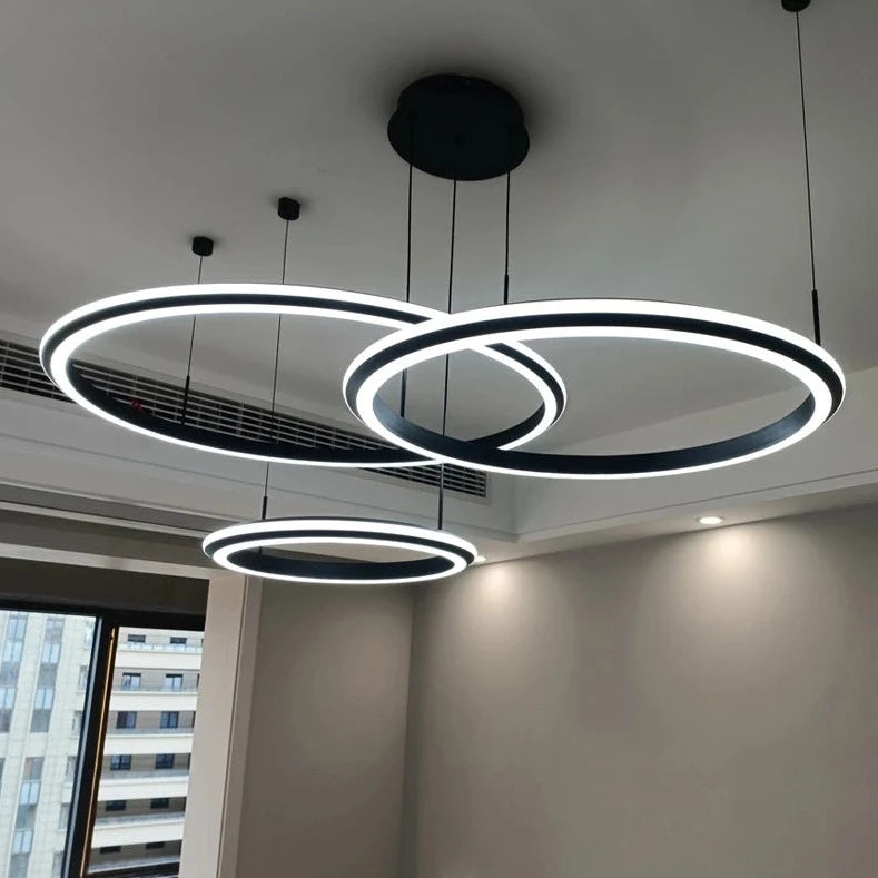Bellezza trio circular chandelier illuminating a sleek monochrome living space.