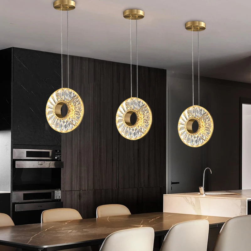Bocelli pendant lights with crystal-adorned rings suspended above a luxury kitchen dining island.