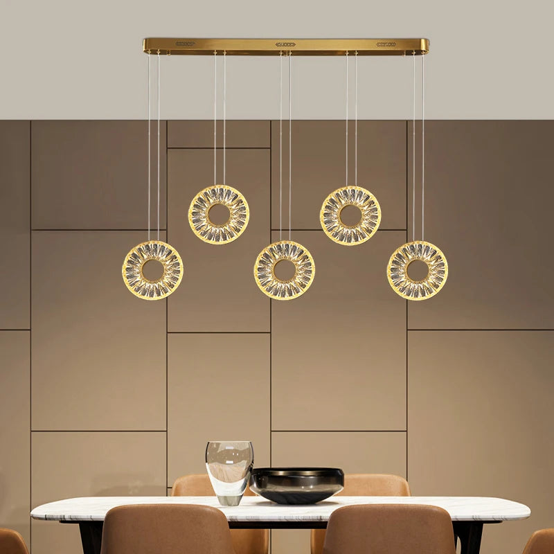 Bocelli rectangular chandelier featuring suspended crystal-adorned rings above a luxury dining table.