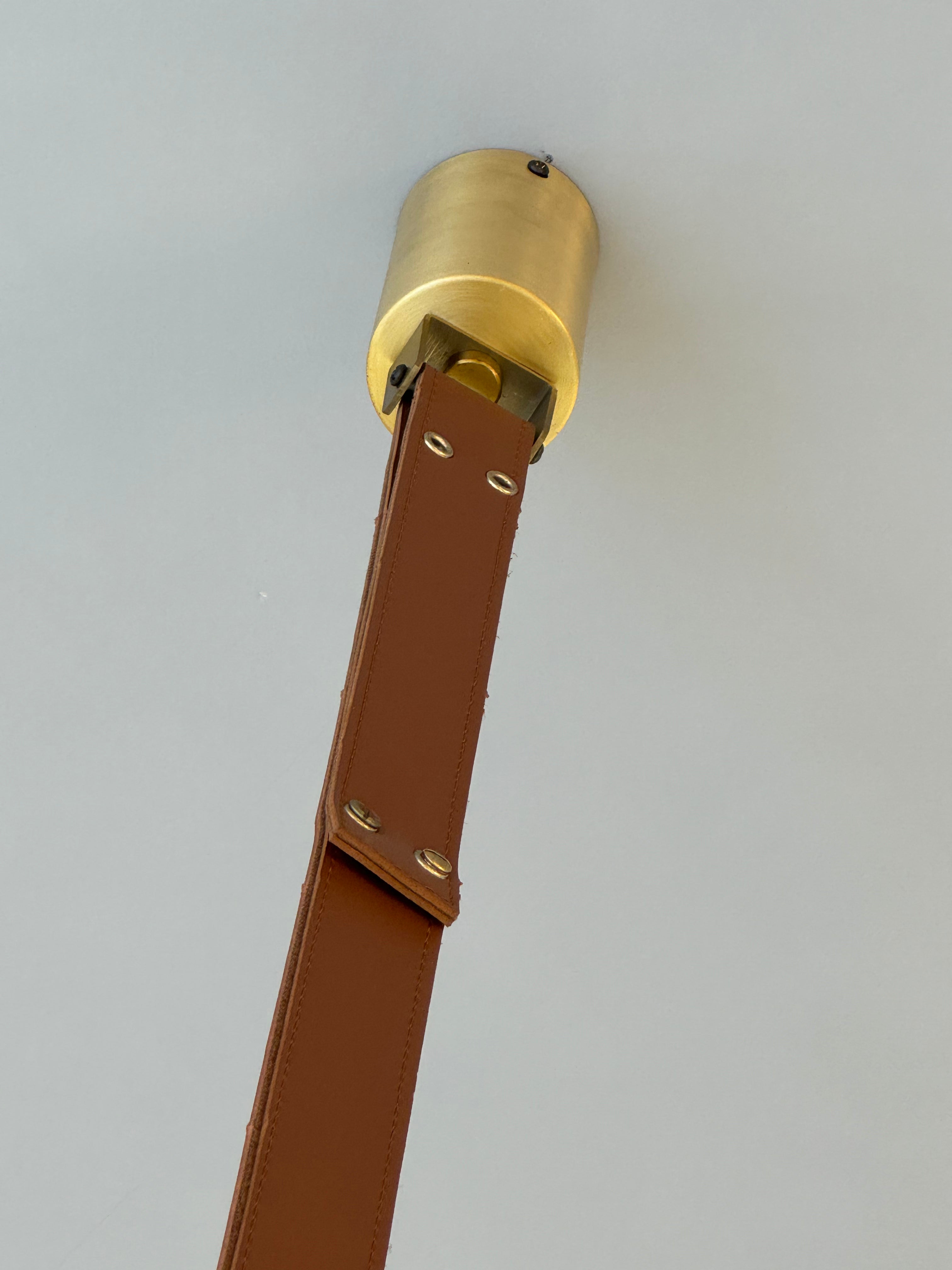 Close-up of the leather suspension strap and brass fixture on the Botticino Marble Pendant Light.