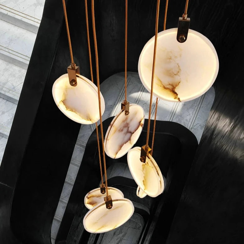 Cluster of illuminated Calacatta marble pendants arranged at varying heights.