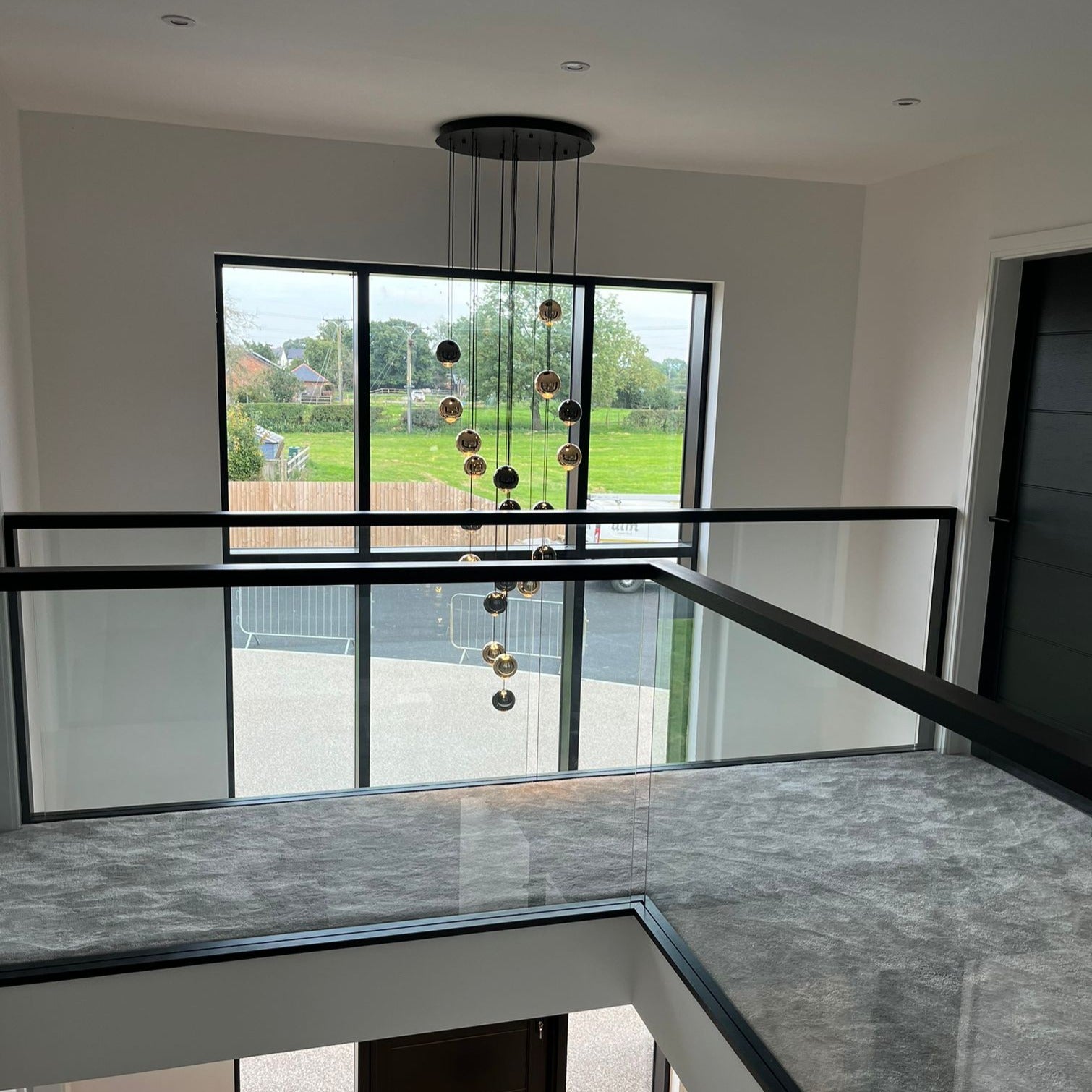 Carlito Staircase Chandelier illuminating a modern staircase with its elegant cascading pendant spheres.