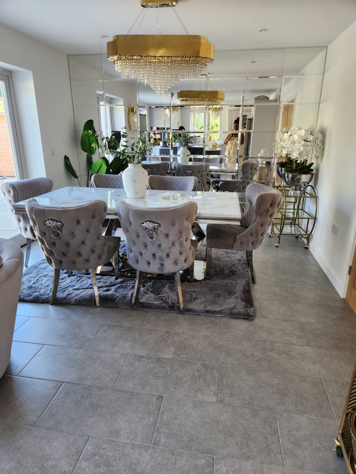 Luxury circular crystal chandelier illuminating an elegant dining room with mirrored walls and marble textures