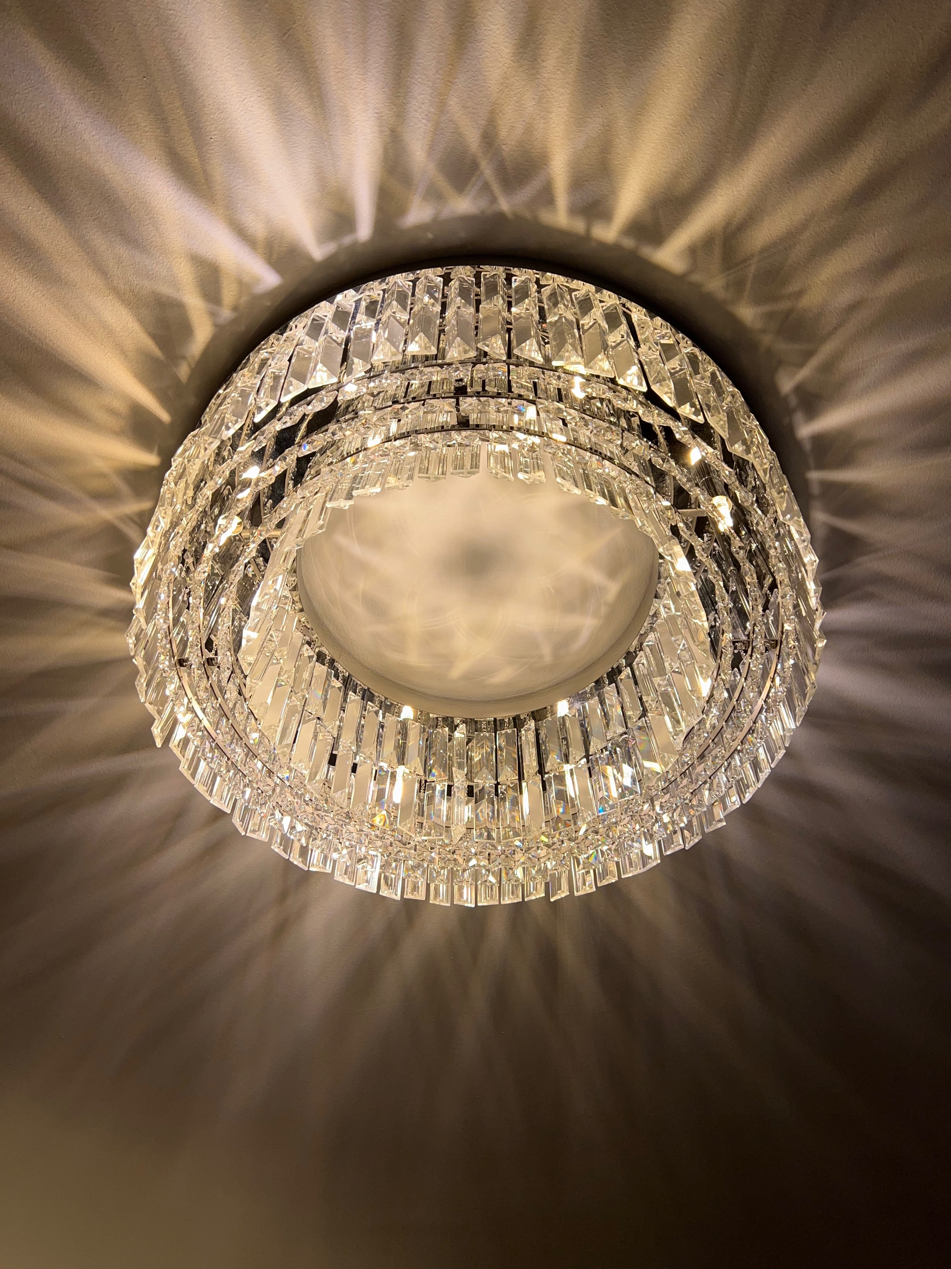 Luxury circular crystal ceiling light elevating a contemporary lounge with soft ambient lighting