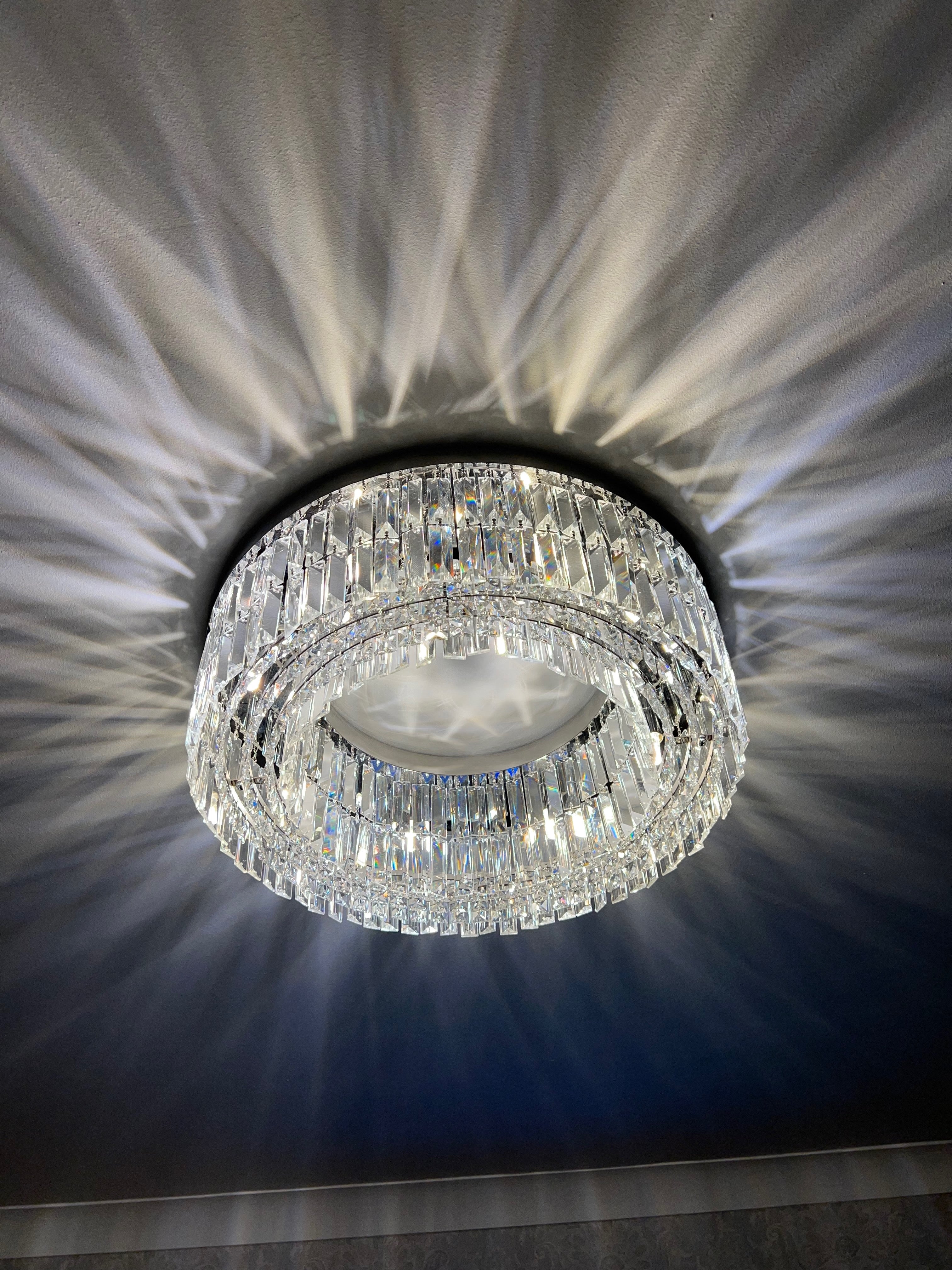Luxury circular crystal ceiling light creating a refined ambient glow in a modern living room interior