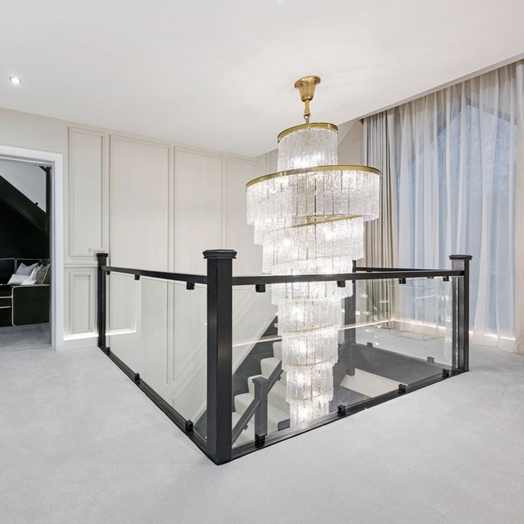 Angled view of the VORELLI Dunleavy spiral staircase chandelier cascading through a modern stairwell
