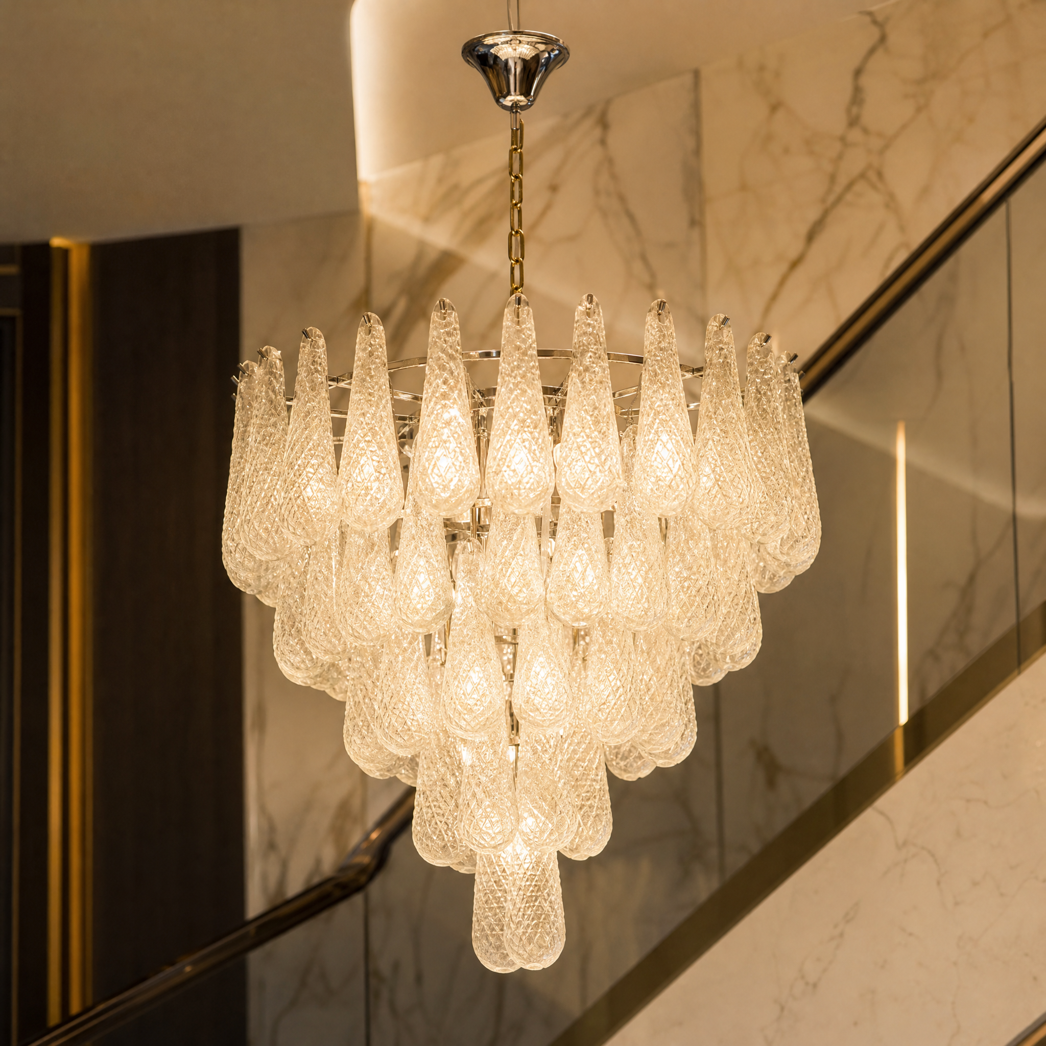 Detailed closeup of the VORELLI Eclissi Grandeur chandelier showcasing the intricate teardrop diamond-cut textured crystals and captivating visual effects.