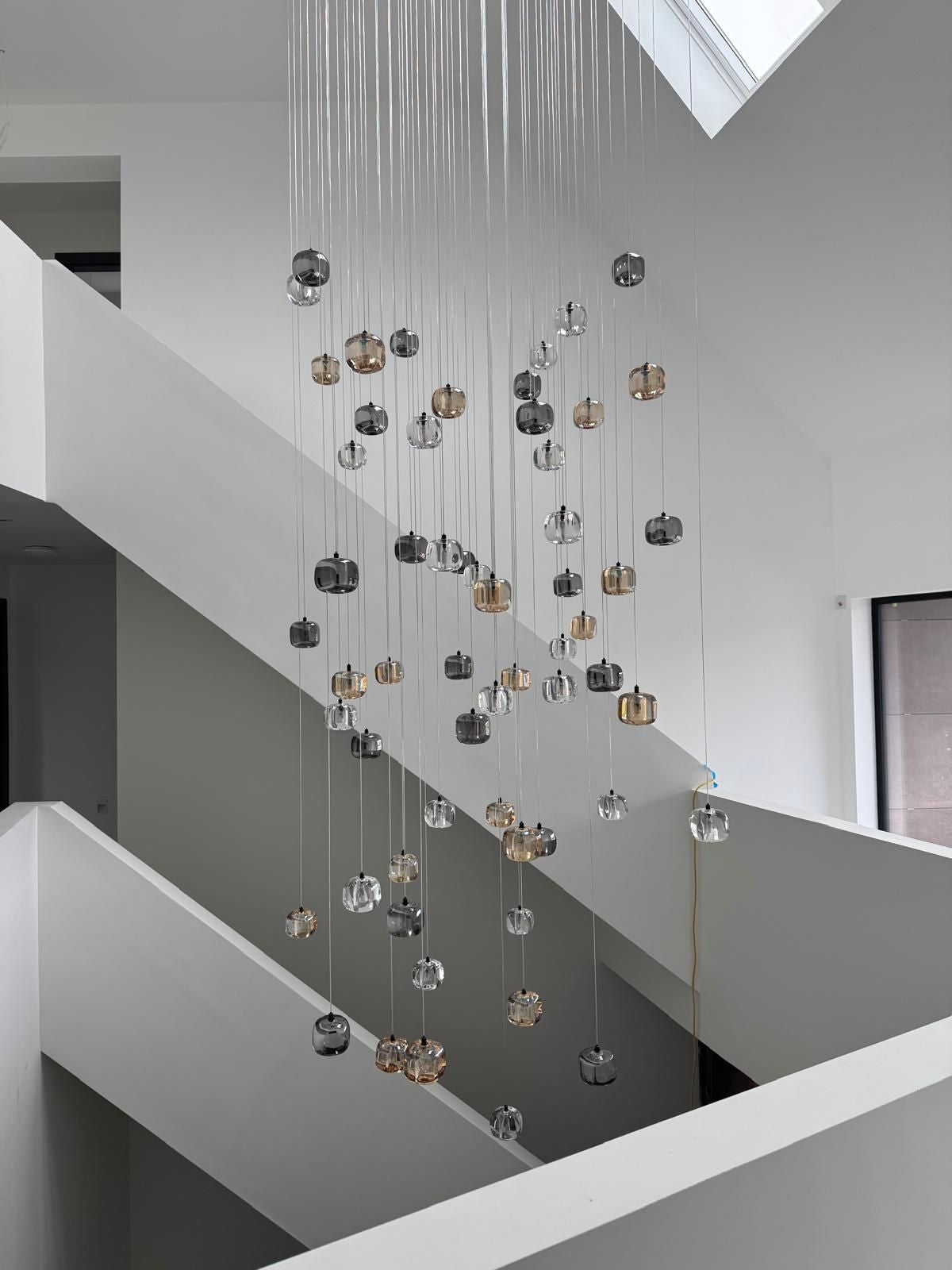 Cascading glass pendant staircase chandelier creating vertical statement lighting