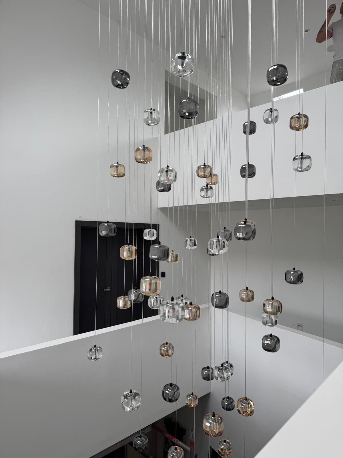 Modern glass pendant staircase chandelier cascading through contemporary stairwell