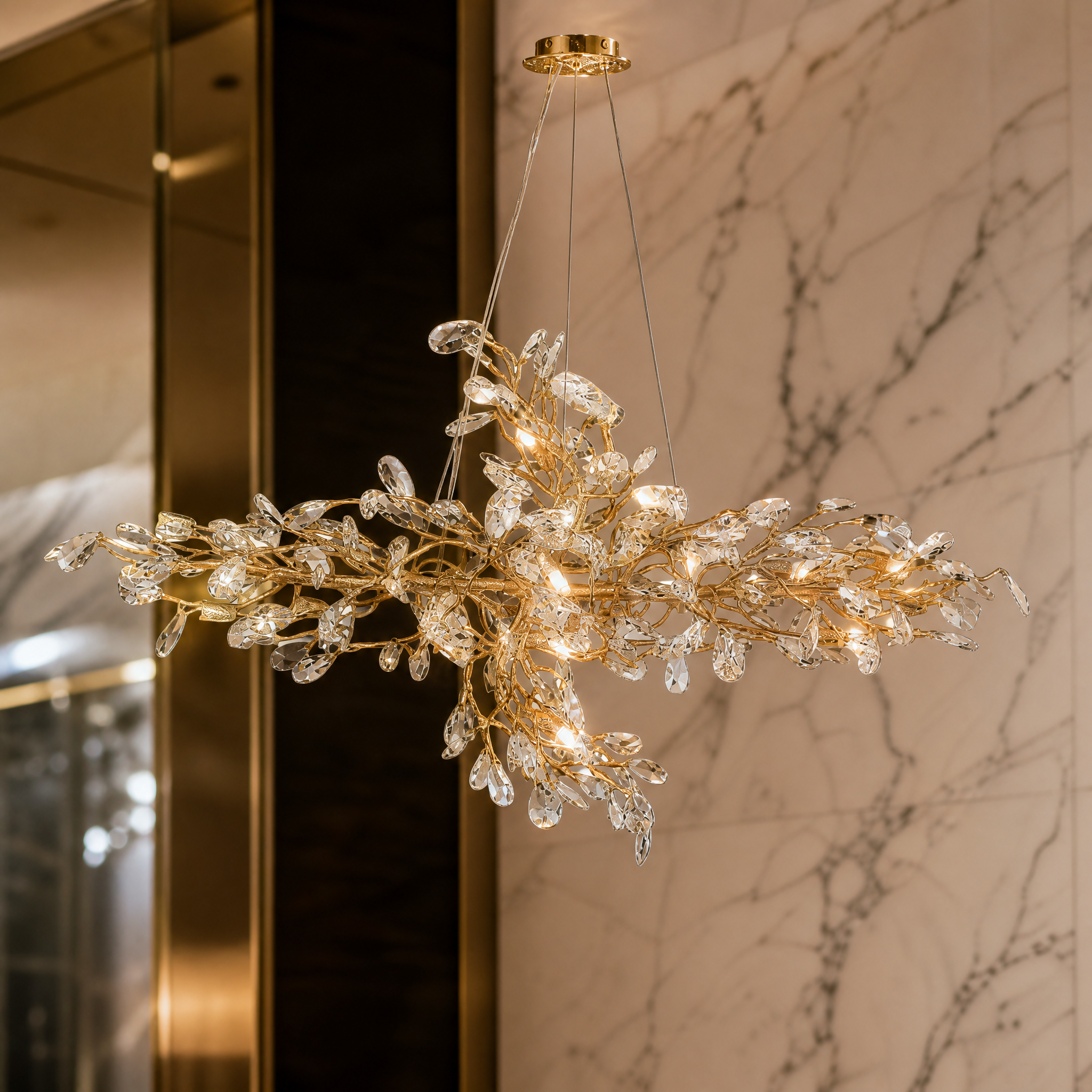 A detailed close-up of the VORELLI Entwine chandelier, showcasing the intricately entwined gold branches and diamond-cut crystal drops refracting light.