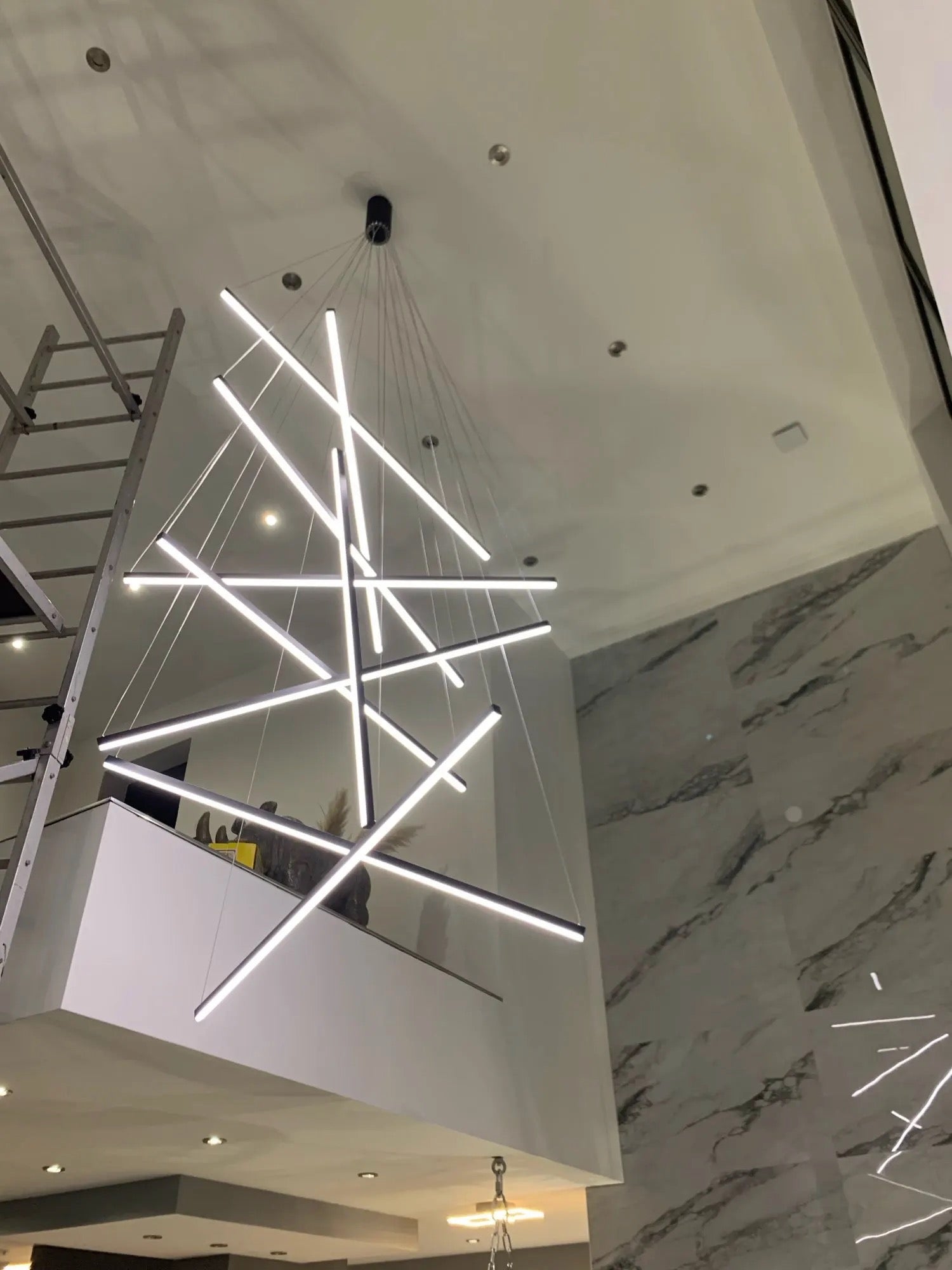 Intersecting linear LED light bars creating a geometric modern chandelier statement