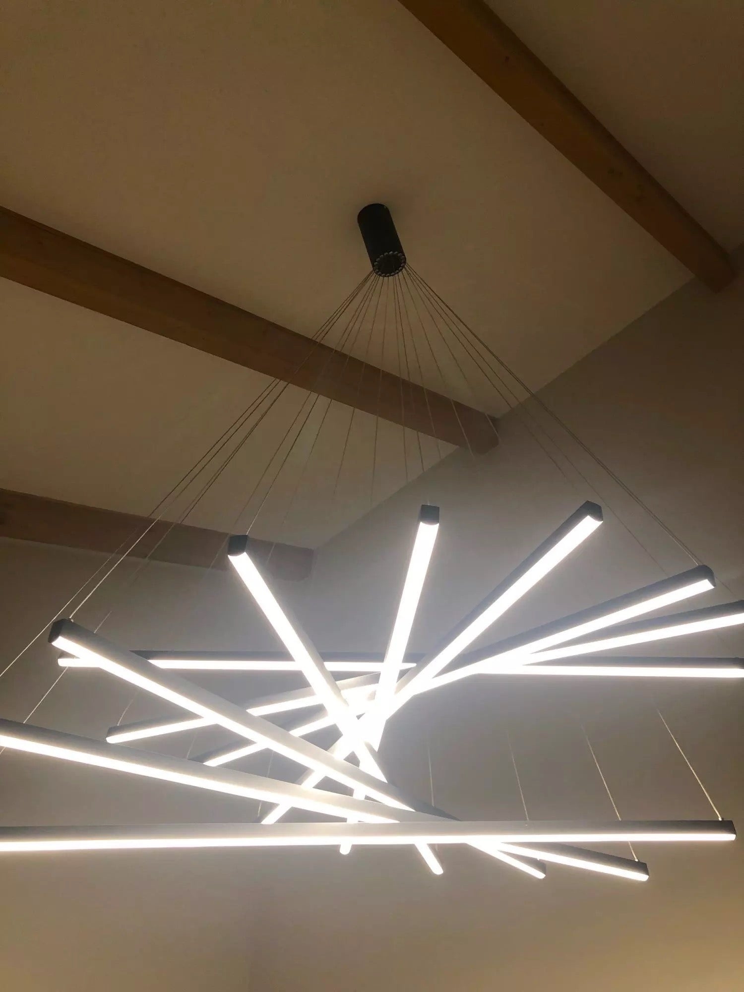 Close-up of ceiling suspension plate and fine cable drops on a contemporary linear LED chandelier