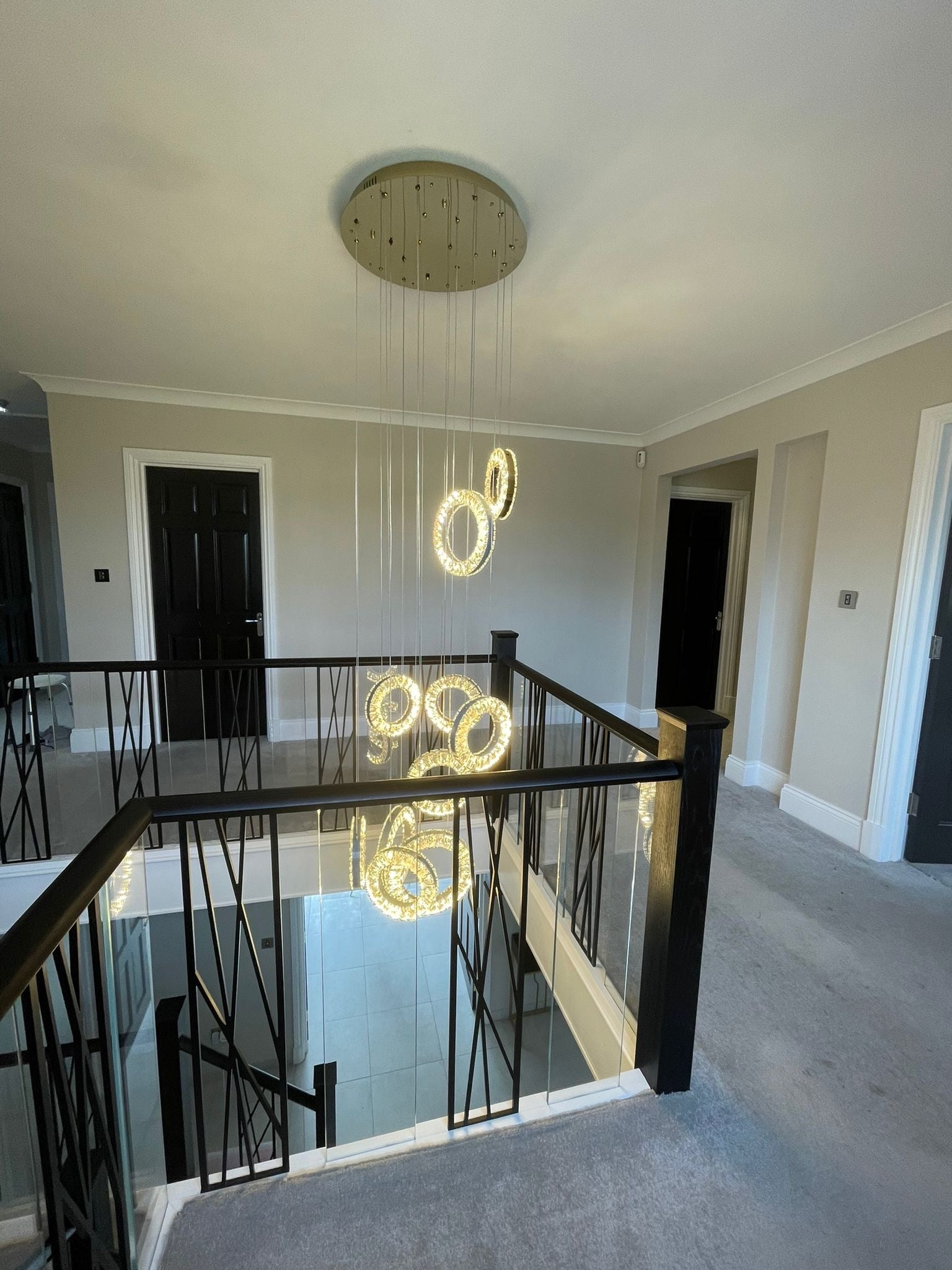 Farnham pendant staircase chandelier with modern LED ring design in a contemporary stairwell interior.