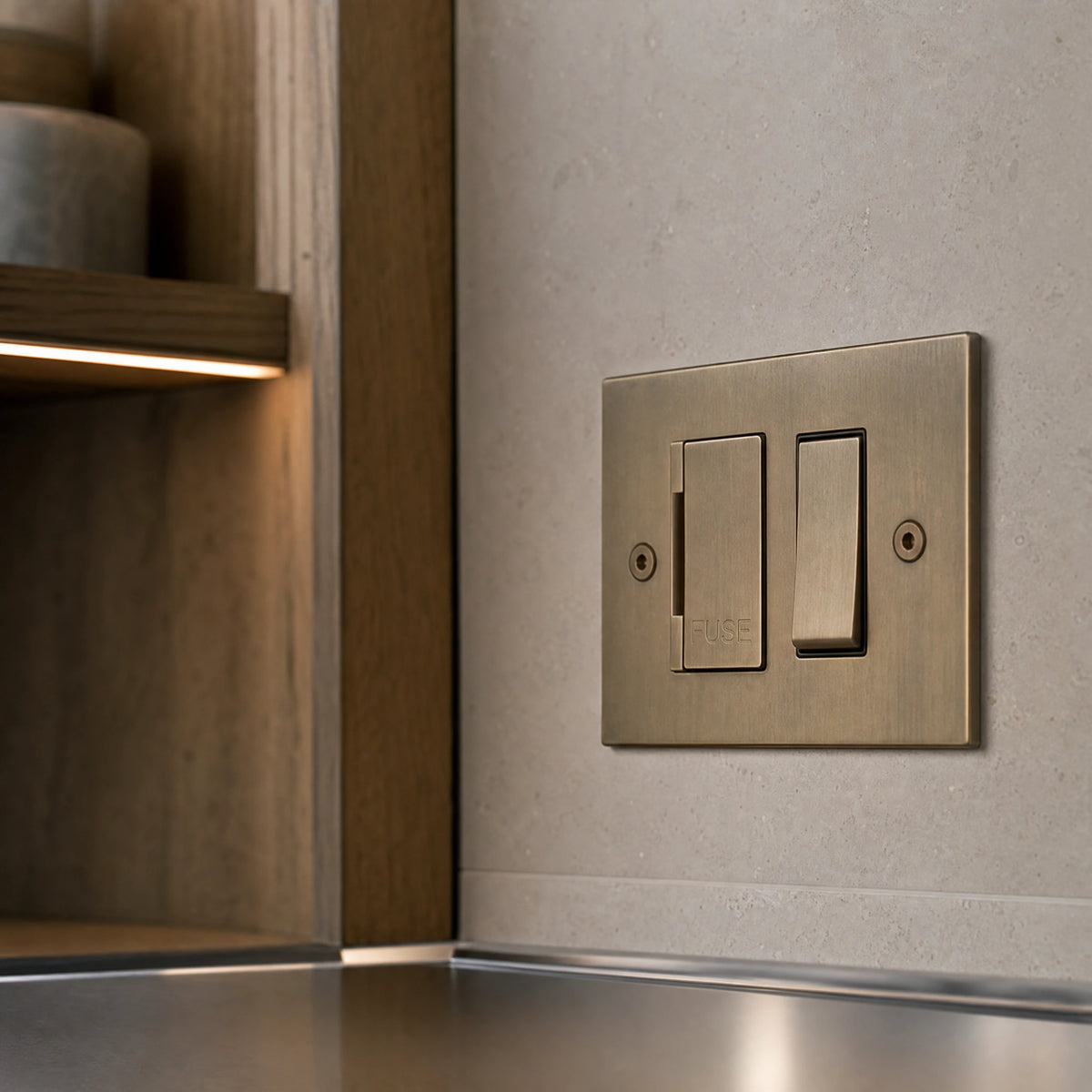 Close-up of a luxury antique brass fused spur installed within discreet below-cabinet utility or kitchen appliance zone in a high-end residence by VORELLI®.