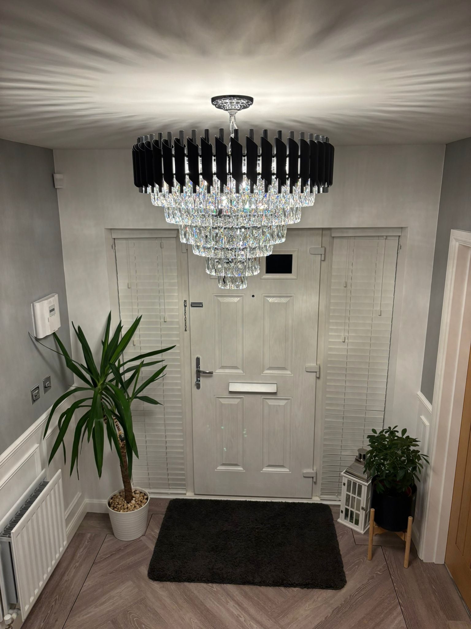 Luxury crystal ceiling chandelier by VORELLI® illuminating a modern hallway entrance with cascading diamond cut faceted crystals and refined contemporary design.