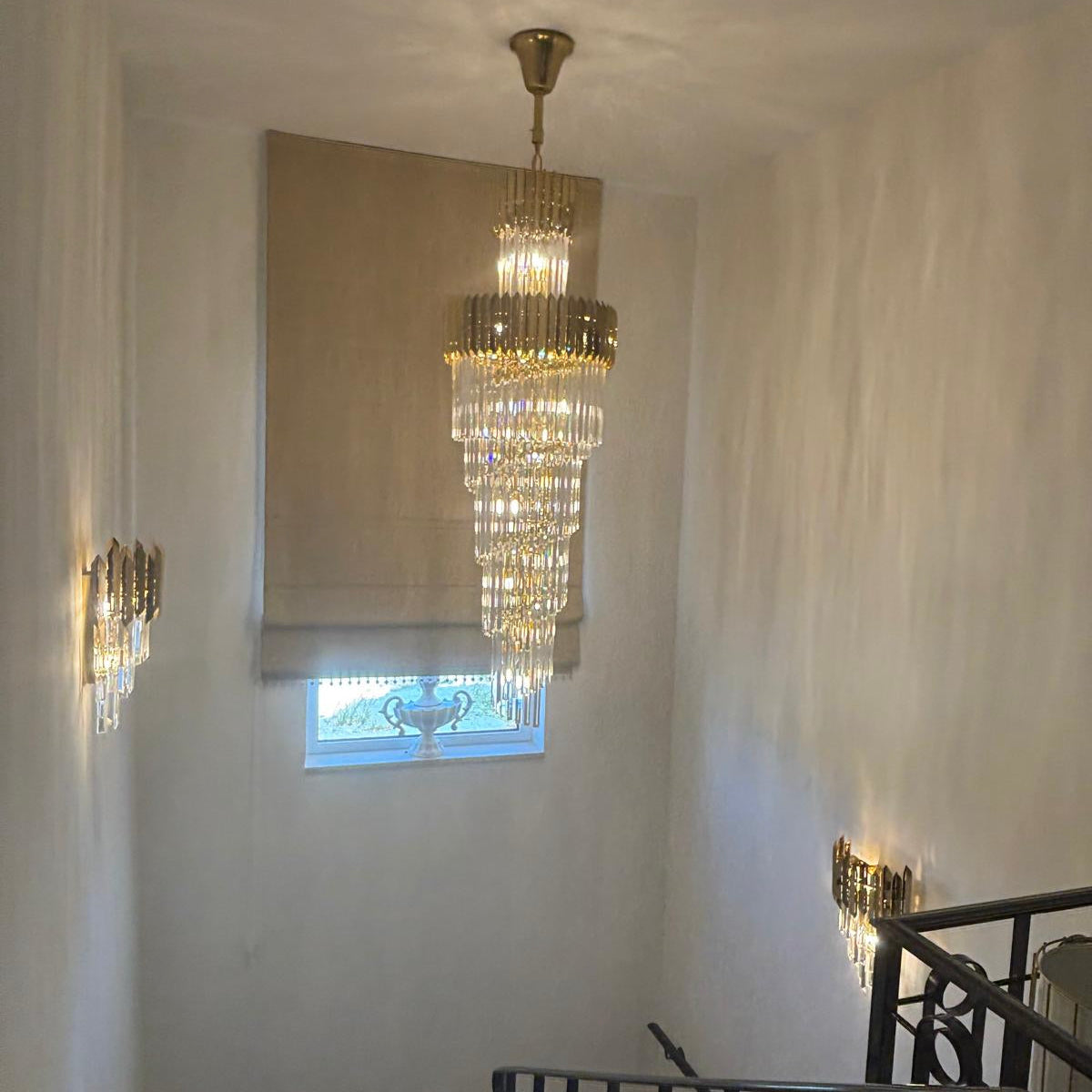 VORELLI® Manhattan spiral staircase chandelier with cascading crystal tiers creating luxury stairwell lighting in a modern residential interior.