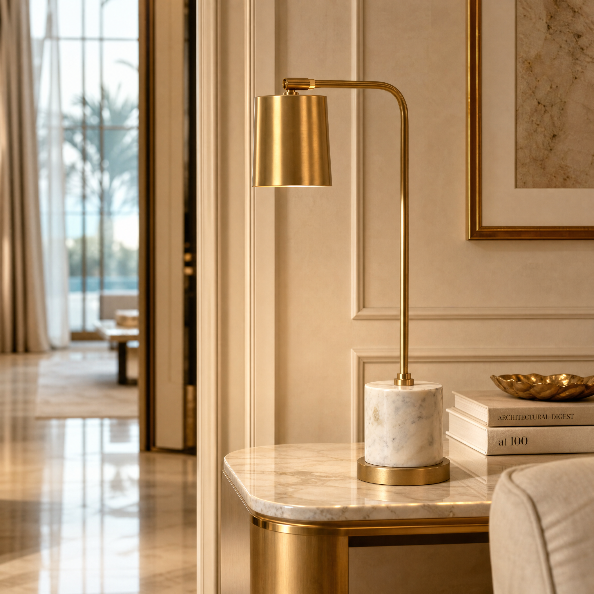 The VORELLI Marcona brass desk lamp illuminating a luxury residential home office setup, showcasing its warm brushed brass finish and white marble base.