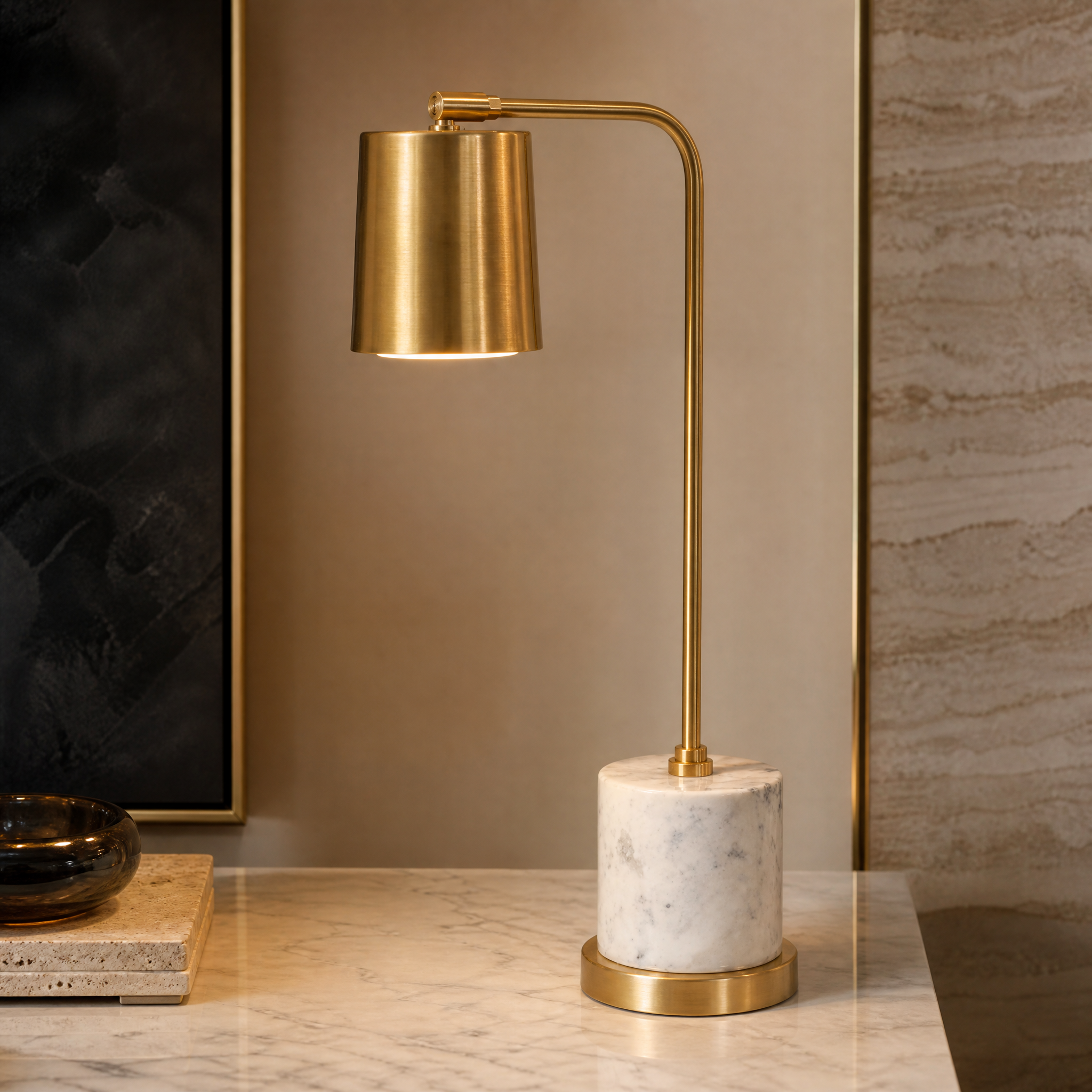 A detailed closeup of the VORELLI Marcona desk lamp, highlighting the sculptural curve of the brass arm and the premium texture of the solid white marble base.