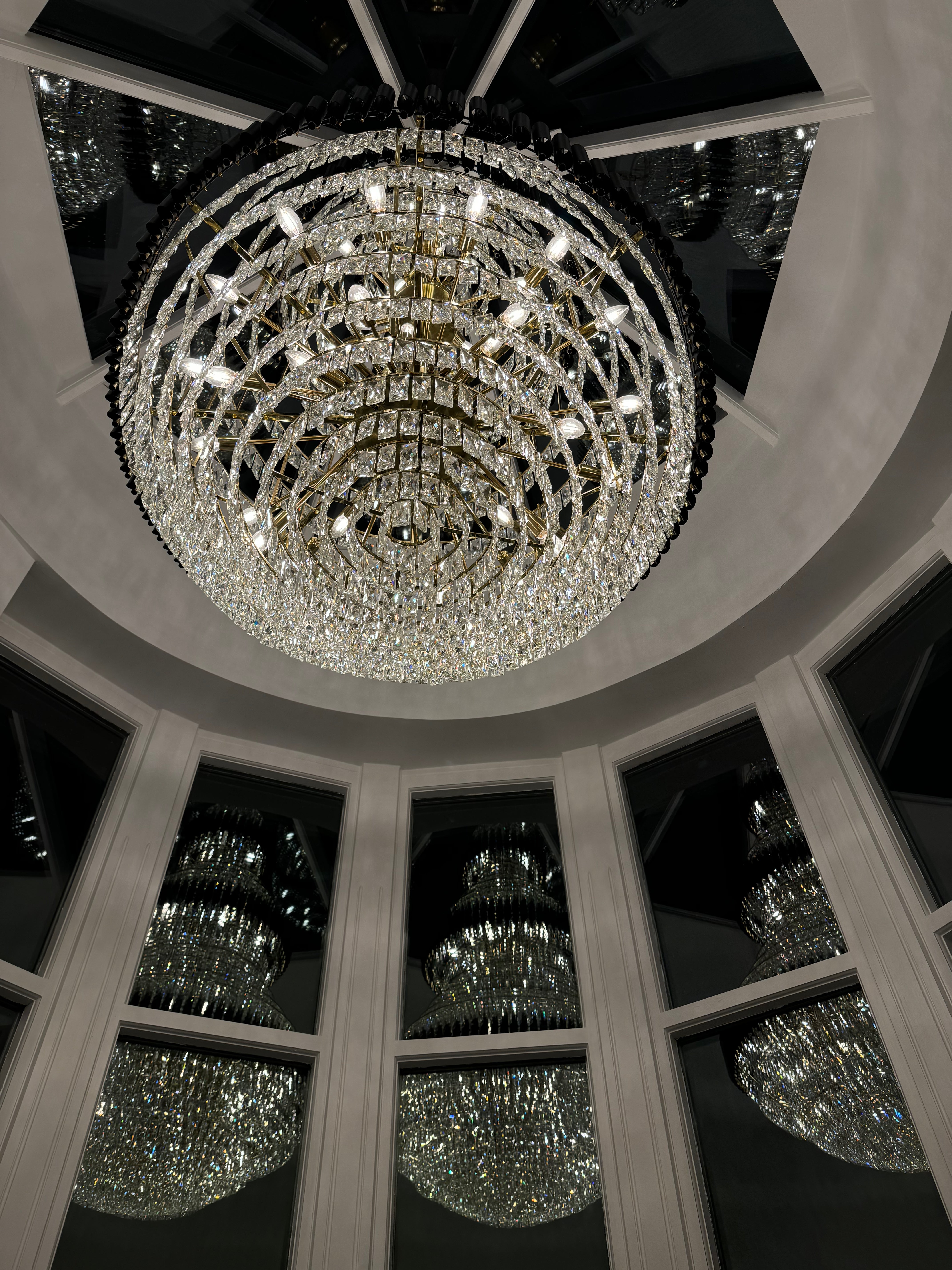 Night silhouette view of the VORELLI Milltimber Grandeur Staircase Chandelier II through architectural glazing