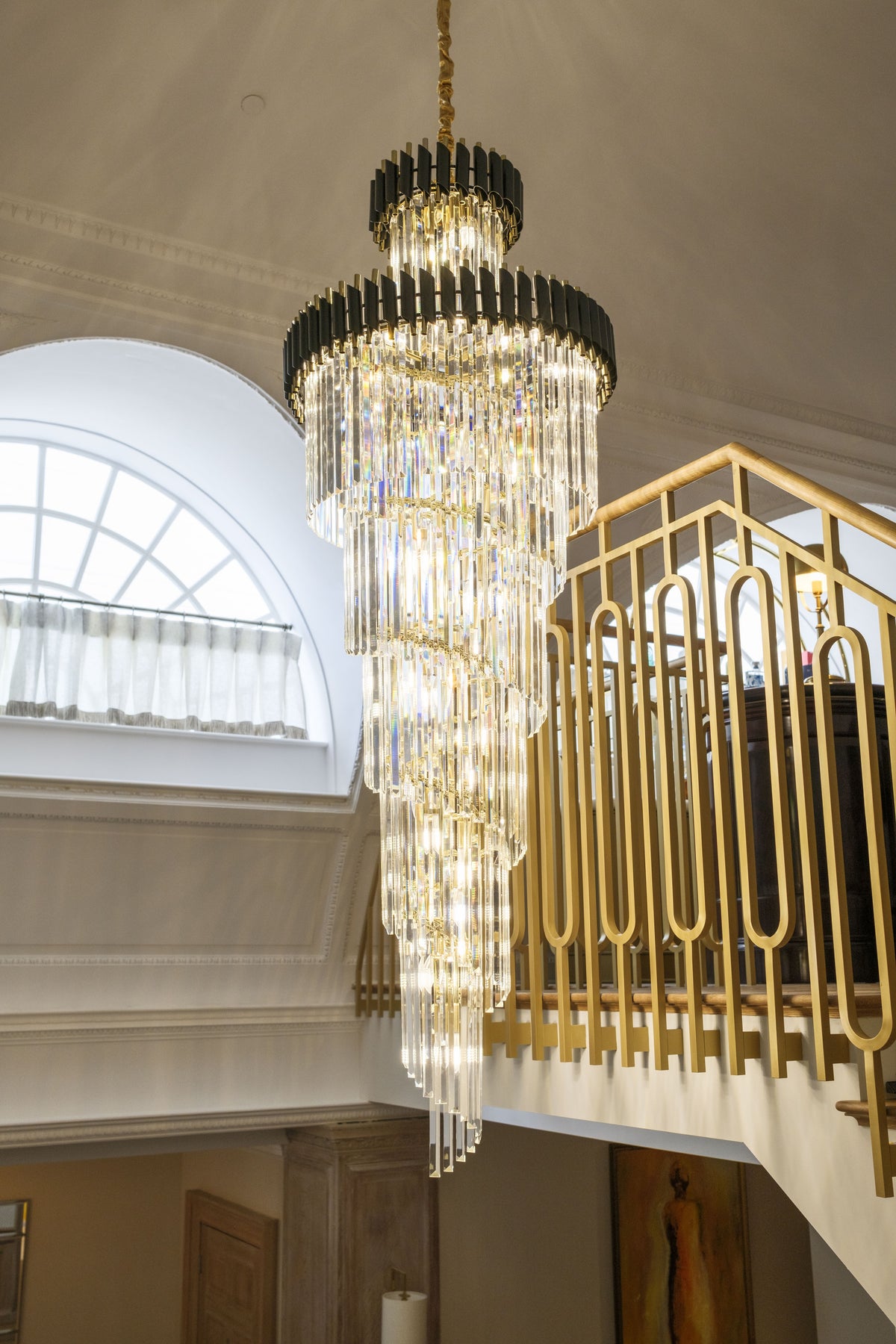 VORELLI Milltimber spiral staircase chandelier with cascading crystal tiers in a double-height entrance hall