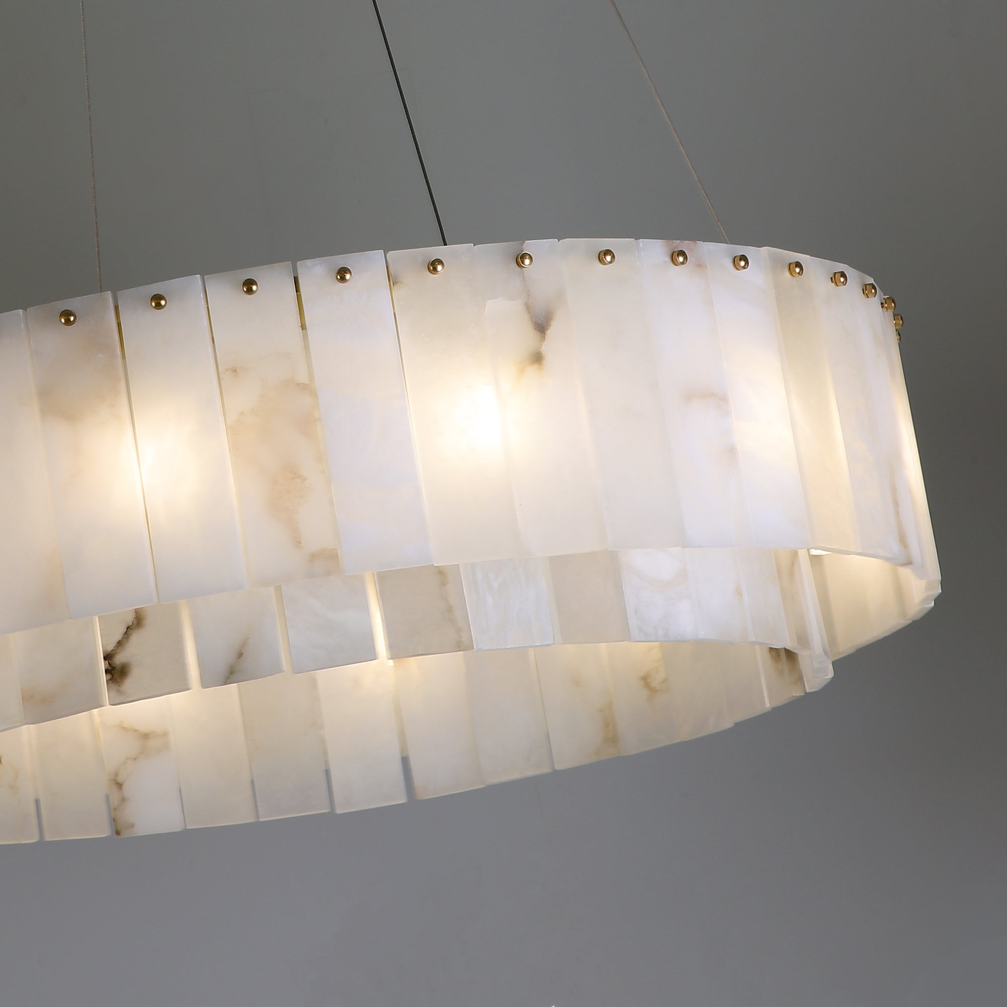 Detailed side view of VORELLI® Munro marble circular chandelier highlighting layered stone panels and warm ambient glow