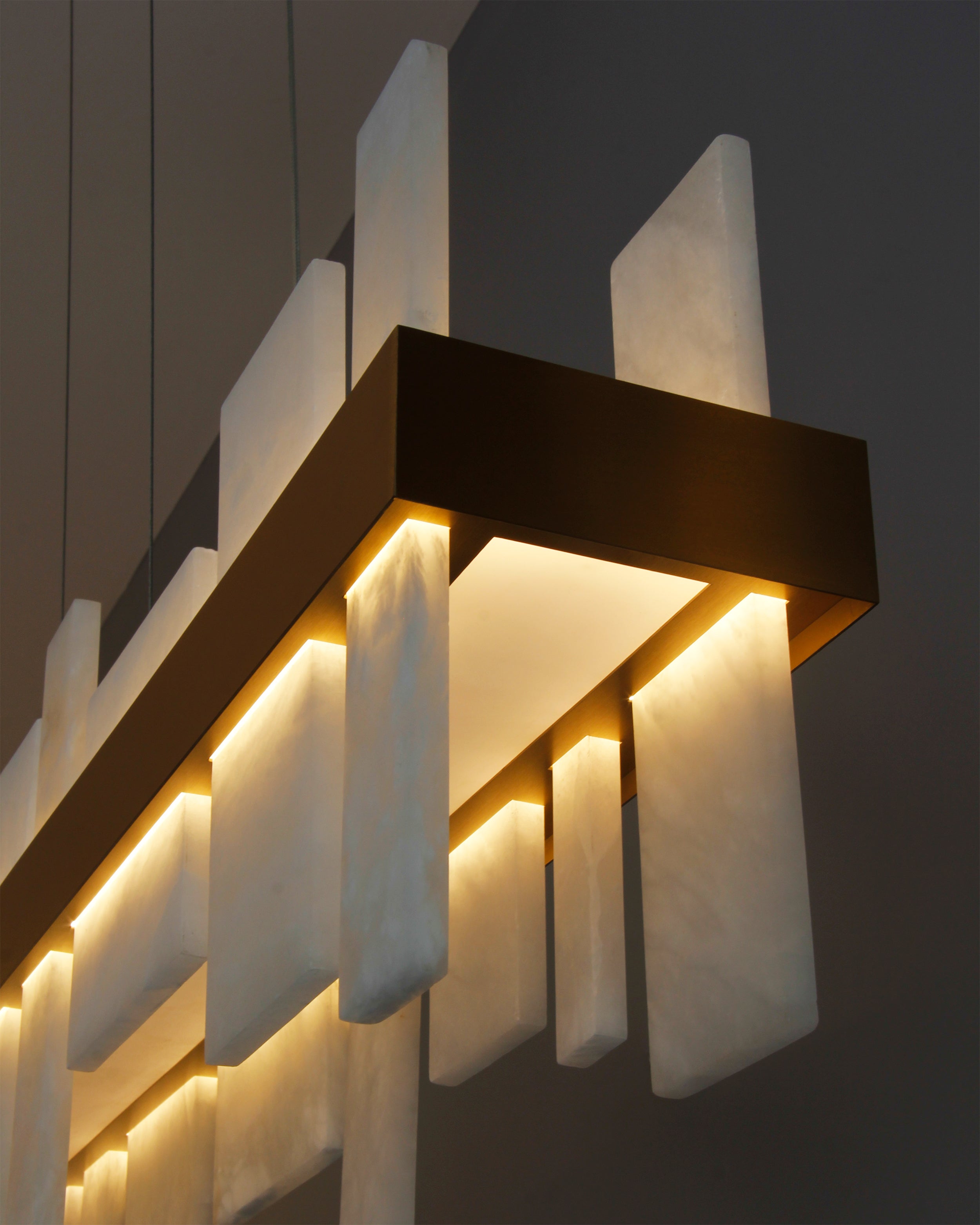 Detailed view of illuminated marble panels on VORELLI® Niva modern rectangular chandelier showcasing warm architectural glow