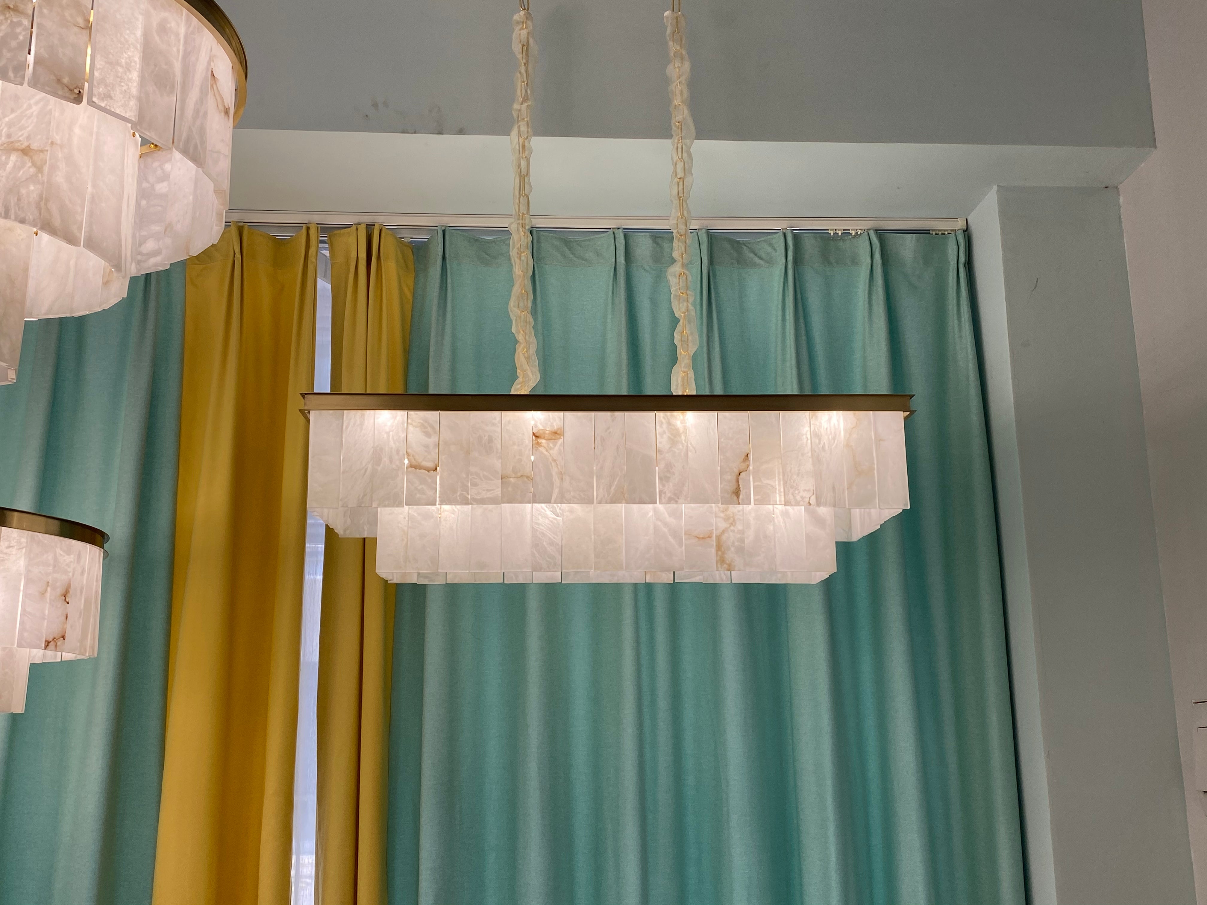 VORELLI® Novella rectangular marble chandelier suspended above dining table creating warm ambient glow