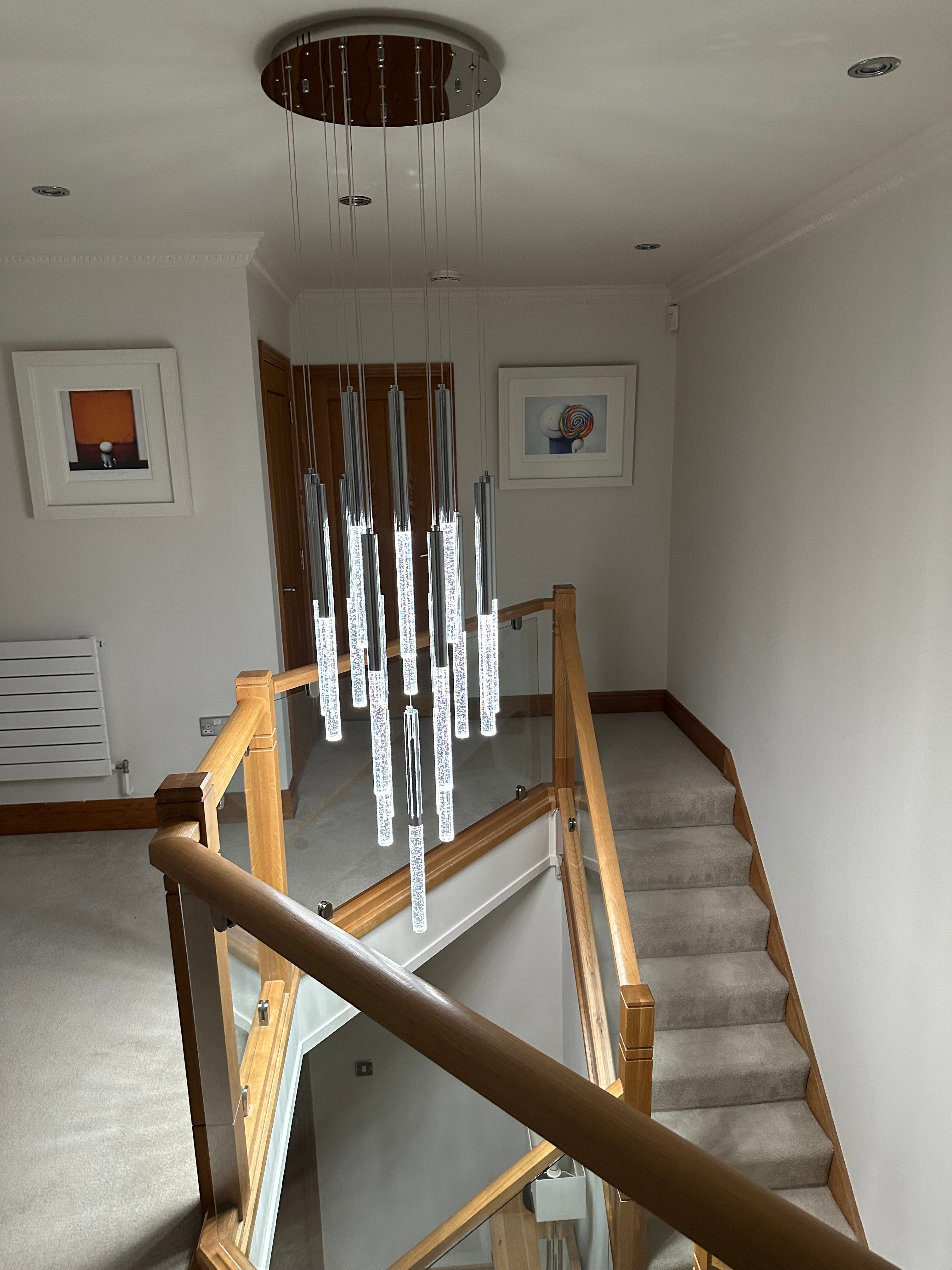 Close up of VORELLI® Nyon pendant staircase chandelier ceiling plate and suspension cables supporting cascading crystal pendants