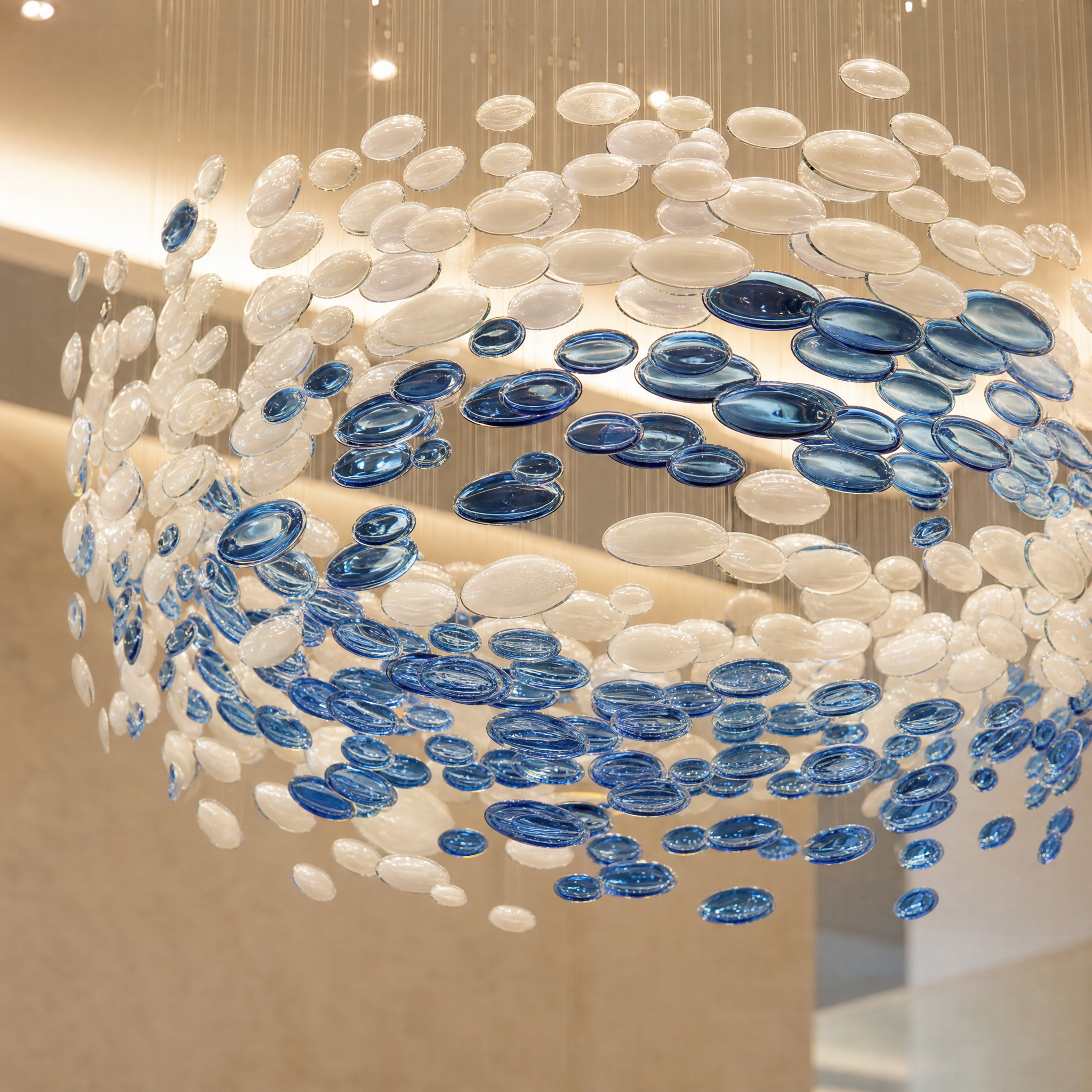 Macro close-up shot of the handcrafted textured glass discs from the Vorelli Orbital Motion chandelier, emphasizing artisan detail.