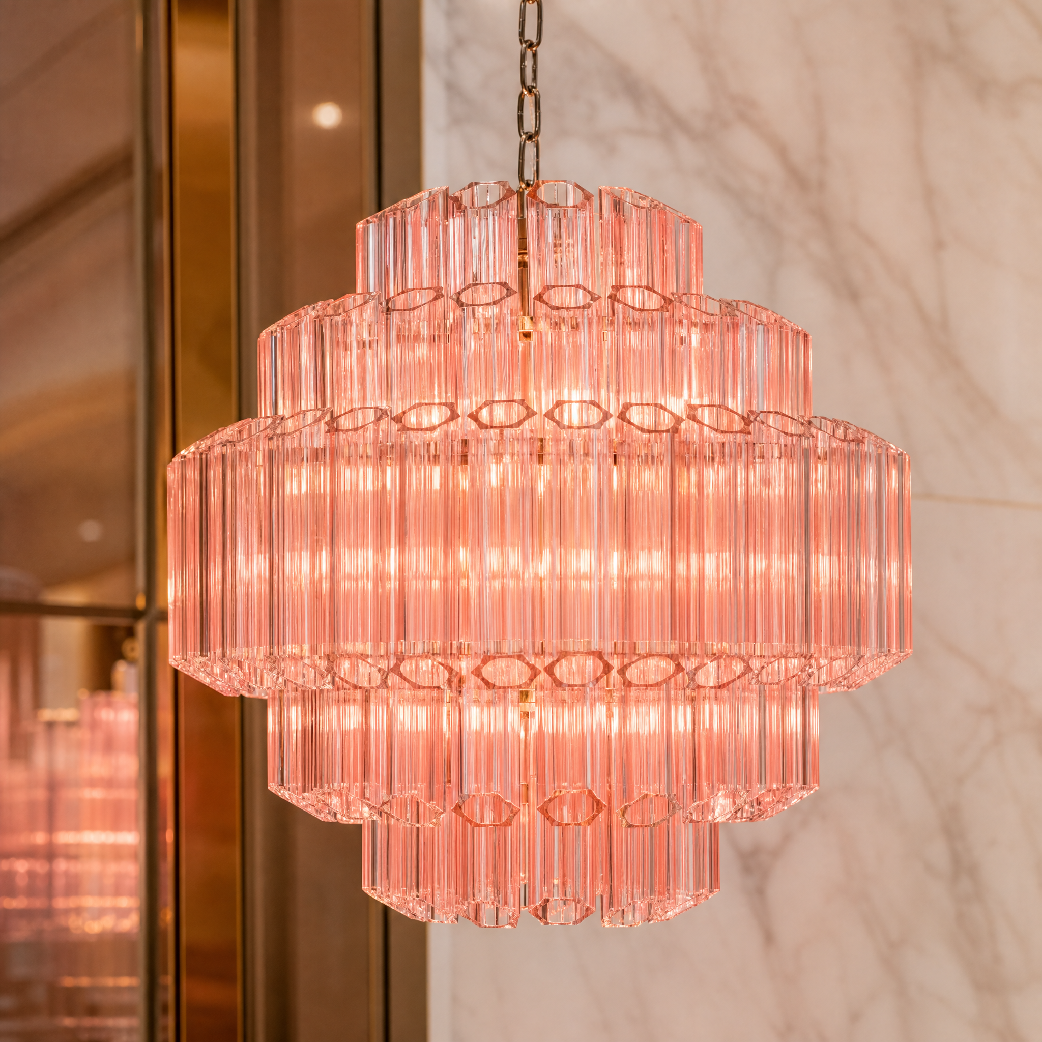 Close-up detail of VORELLI Palermino chandelier showing hexagonal pink glass tubes suspended from a chrome-plated iron frame.