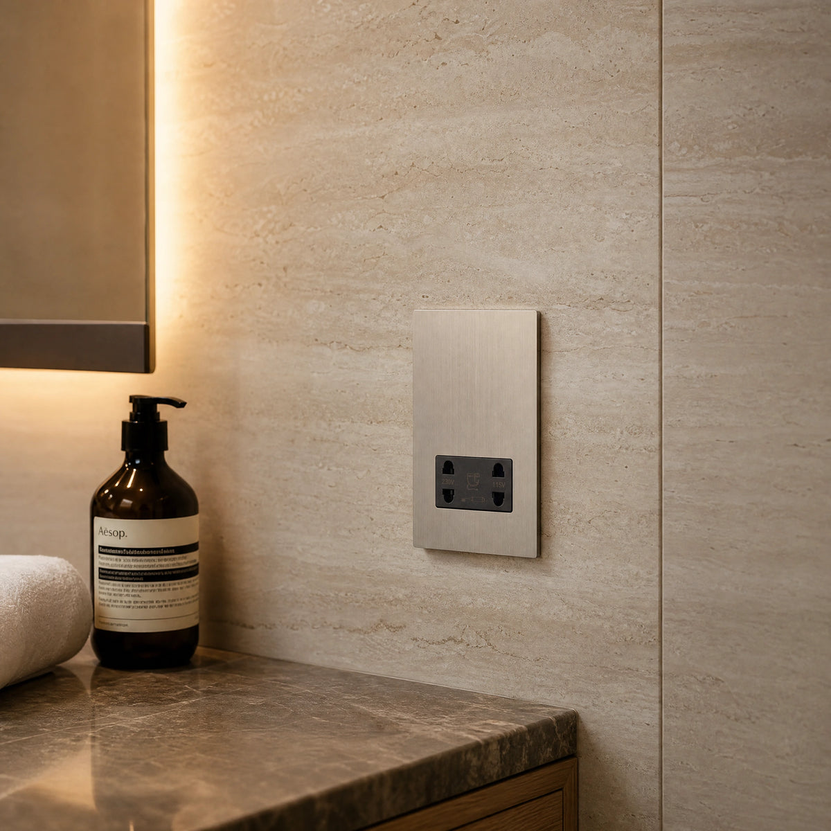 Close-up of a luxury roma shaver socket installed within five-star hotel bathroom vanity with marble wall and soft mirror lighting by VORELLI®.