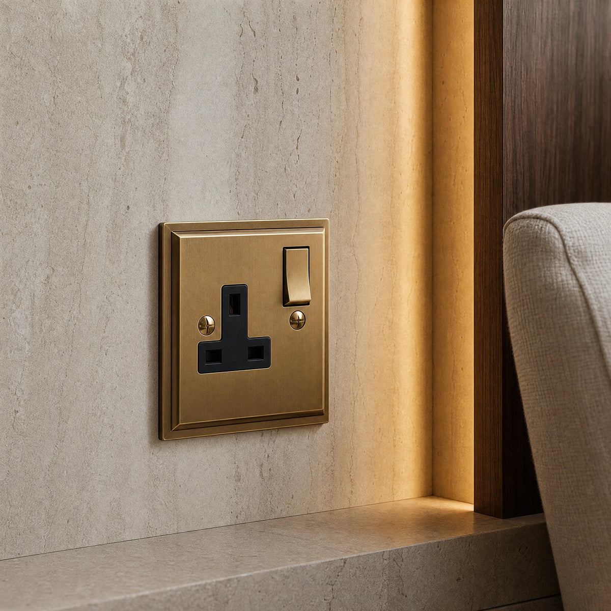 Close-up of a luxury antique brass single socket installed within bespoke bedside joinery or stone wall beside a luxury seating area by VORELLI®.