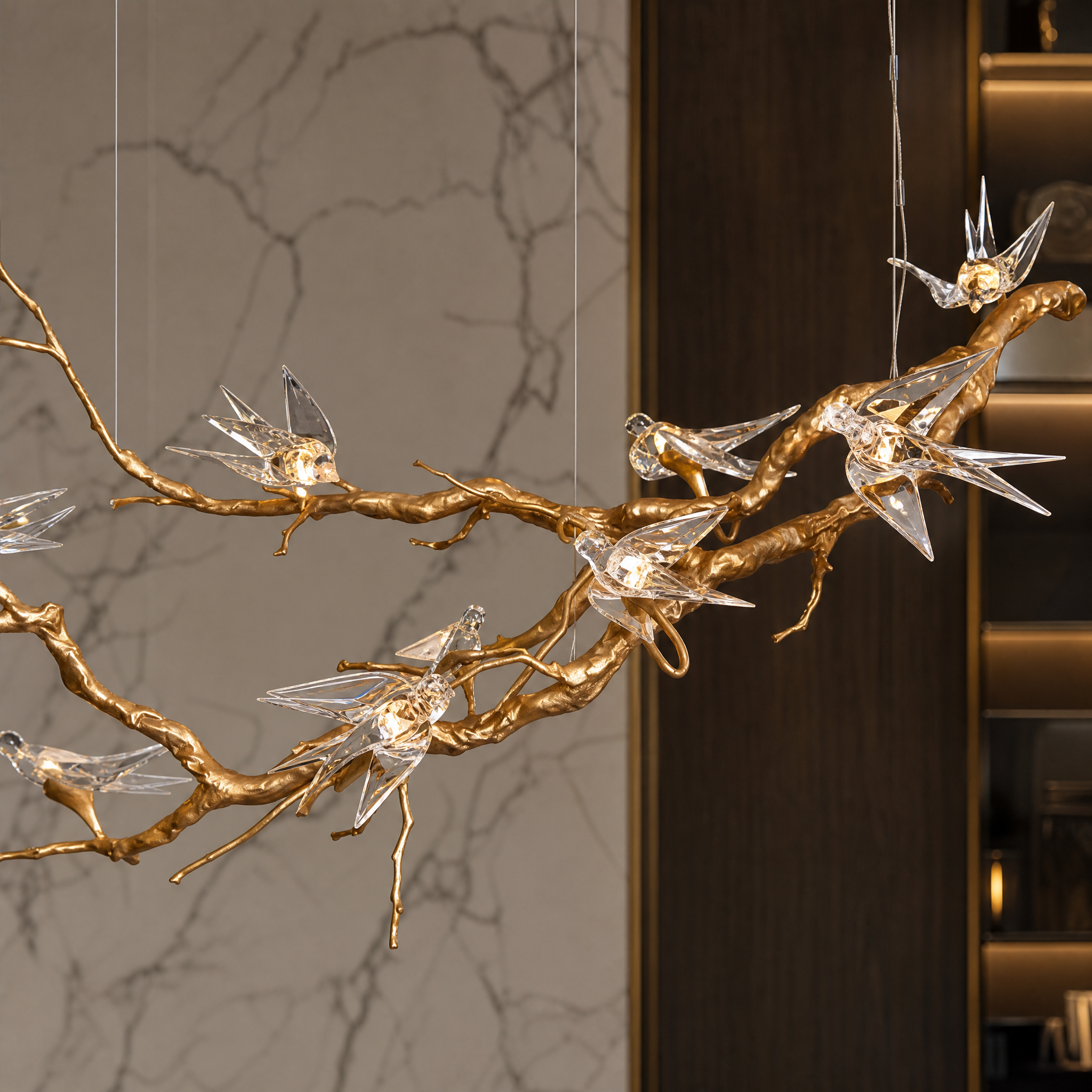 A close-up shot of the delicate crystal bird detailing and nature-inspired branch components of the VORELLI Swallow Bird Chandelier.