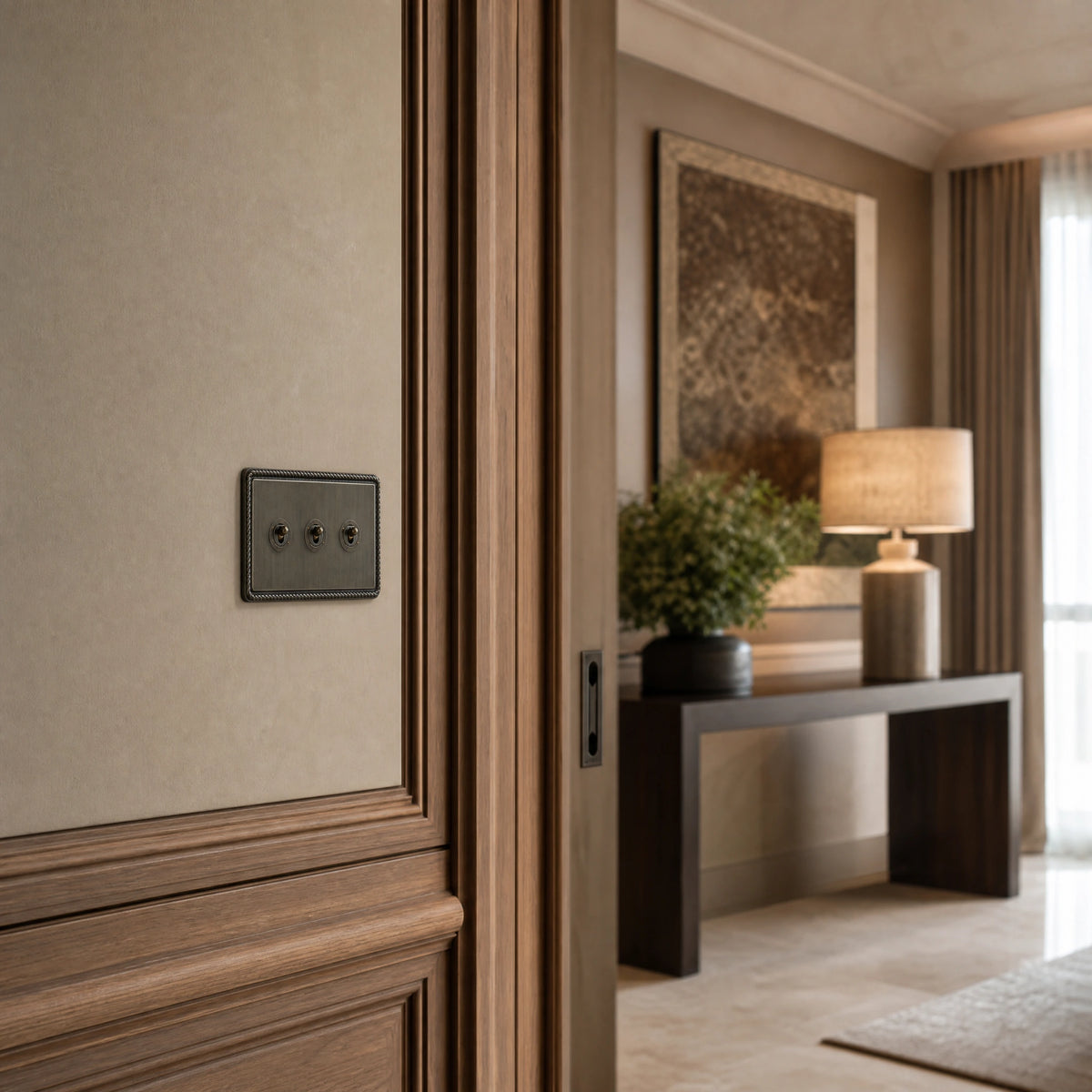 Luxury antique brass toggle switch installed within feature wall beside an elegant doorway with refined timber panelling in a UHNW interior by VORELLI®.