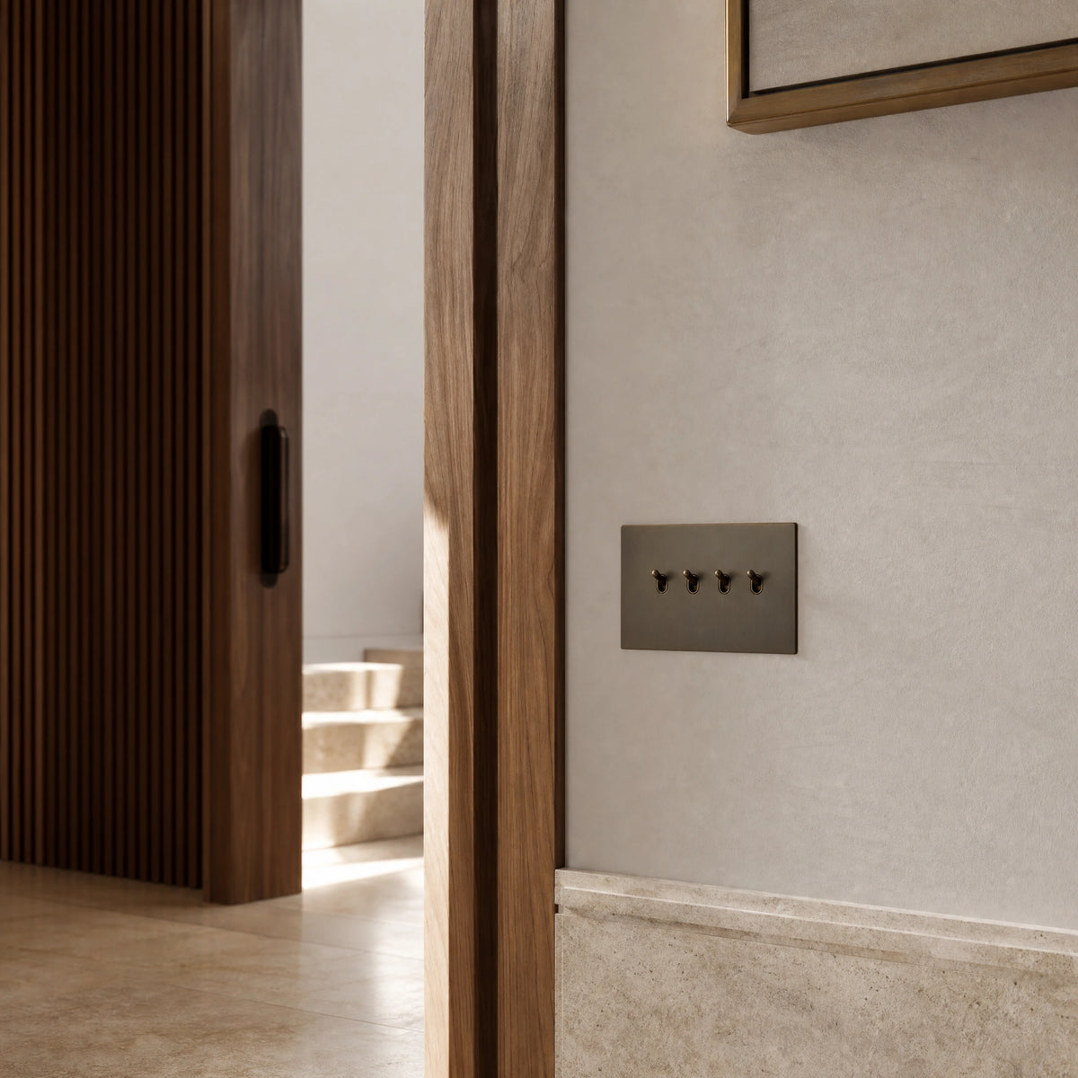 Luxury sienna toggle switch installed within feature wall beside an elegant doorway with refined timber panelling in a UHNW interior by VORELLI®.