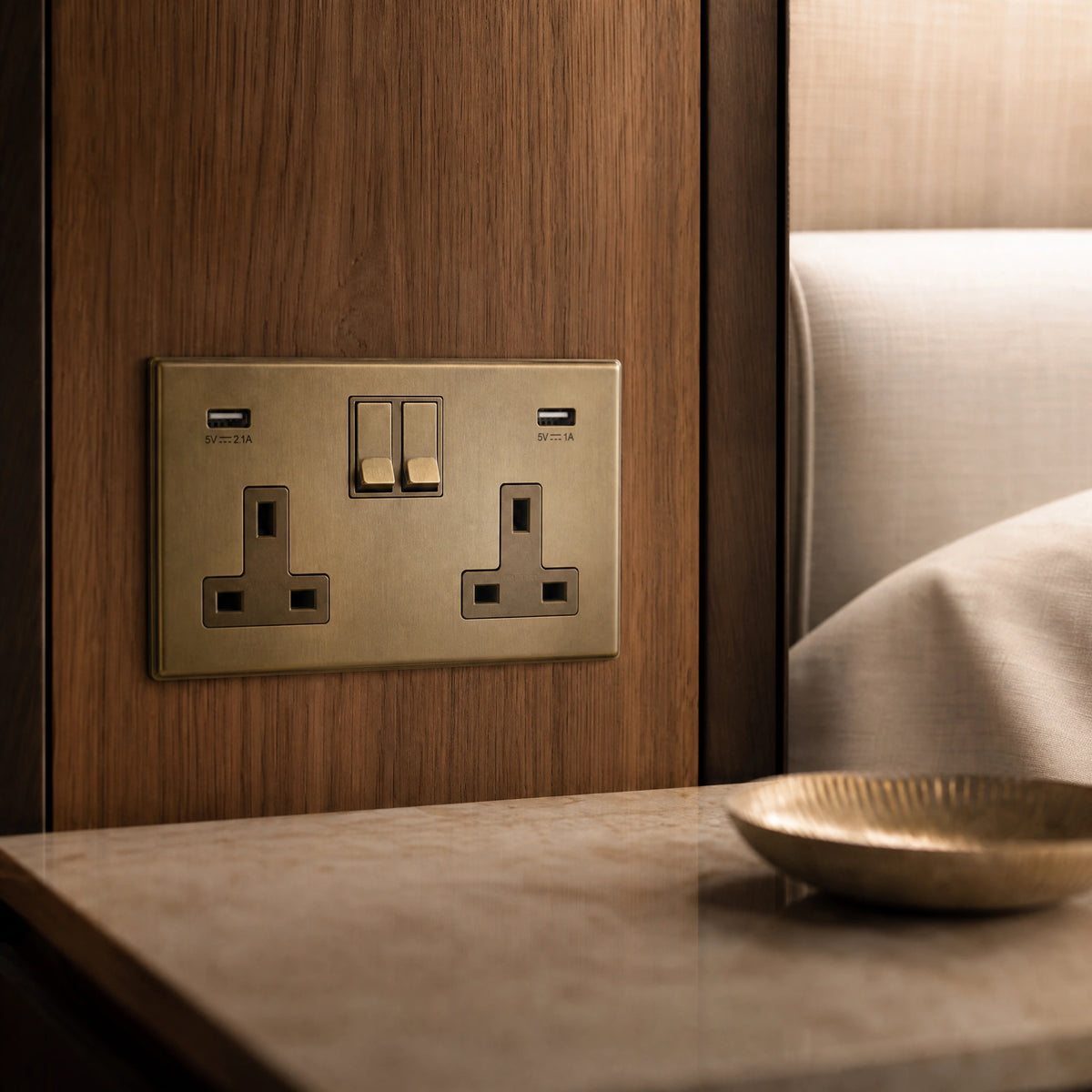 Close-up of a luxury antique brass usb socket installed within bespoke bedside joinery in a luxury bedroom suite by VORELLI®.