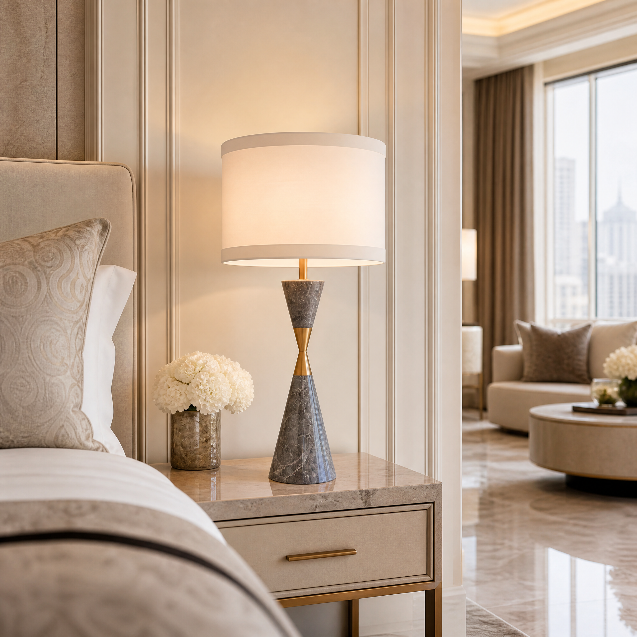 VORELLI Zavaro grey marble and antique brass table lamp casting a soft ambient glow on a modern bedside table in a luxury residential bedroom.