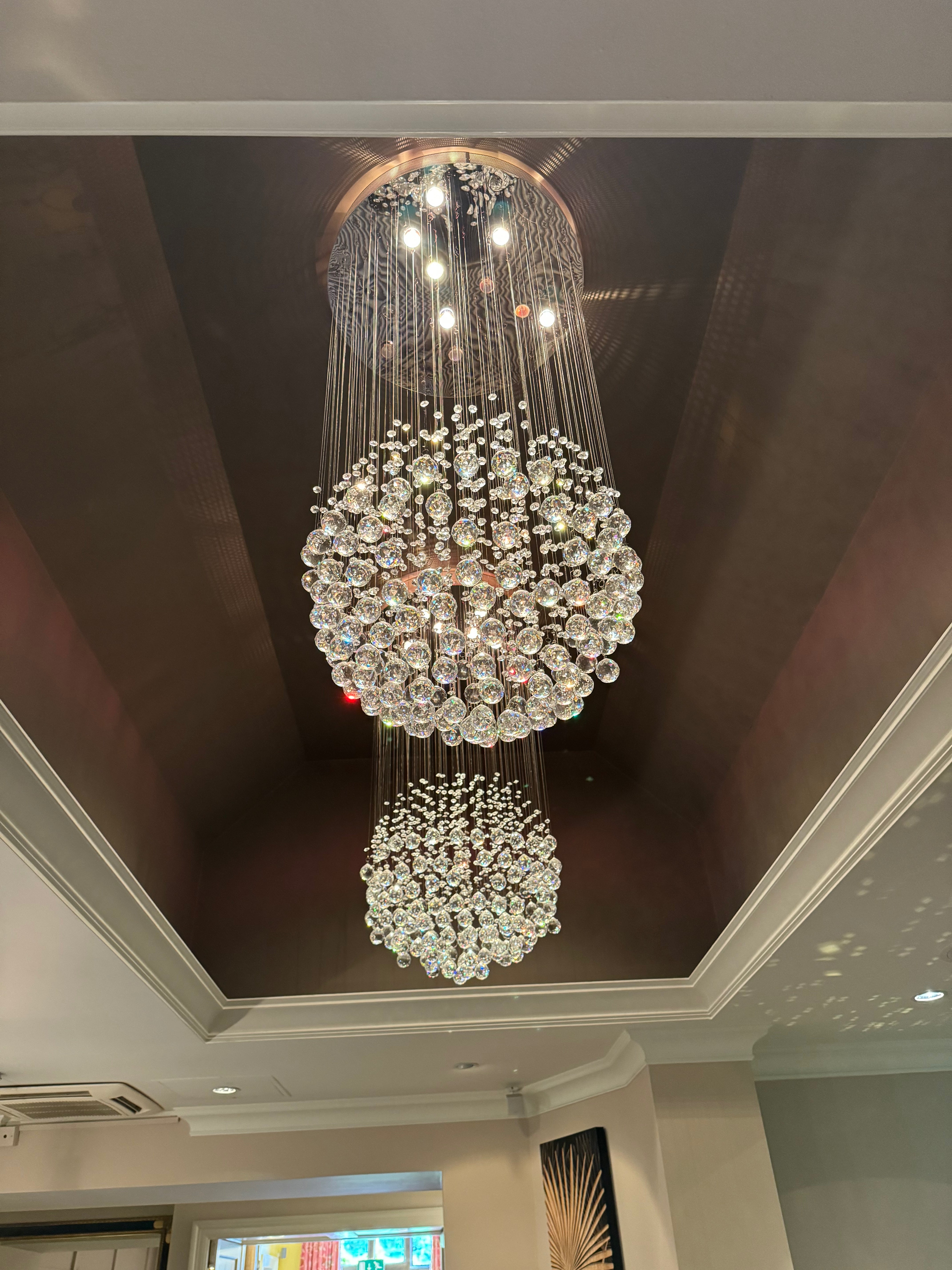 Vertical view of Whirlow staircase chandelier with diamond cut flower crystals cascading from ceiling