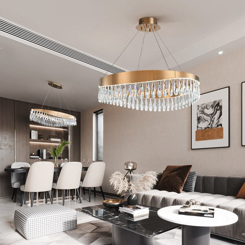 Designer circular crystal chandelier suspended above a dining table in a refined modern interior setting